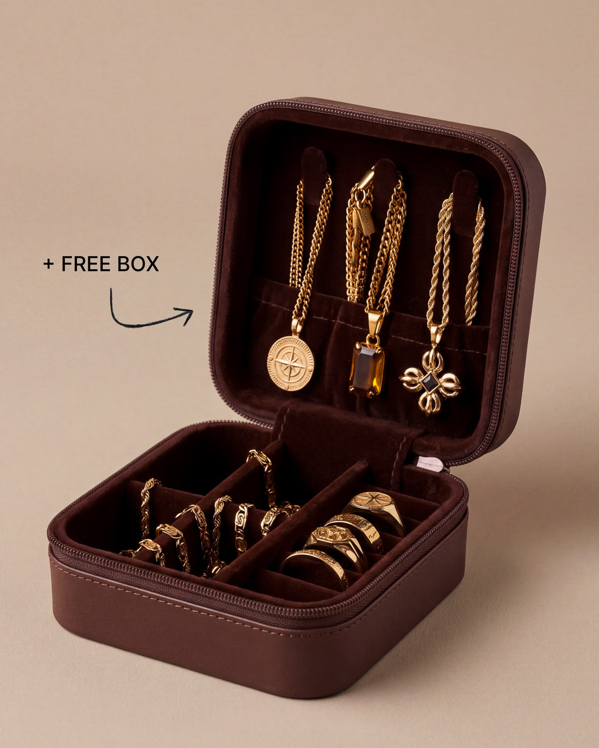 Joyero de viaje marrón abierto con la oferta de caja gratis, con tres collares dorados con colgante, pulseras de cadena dorada y anillos sello