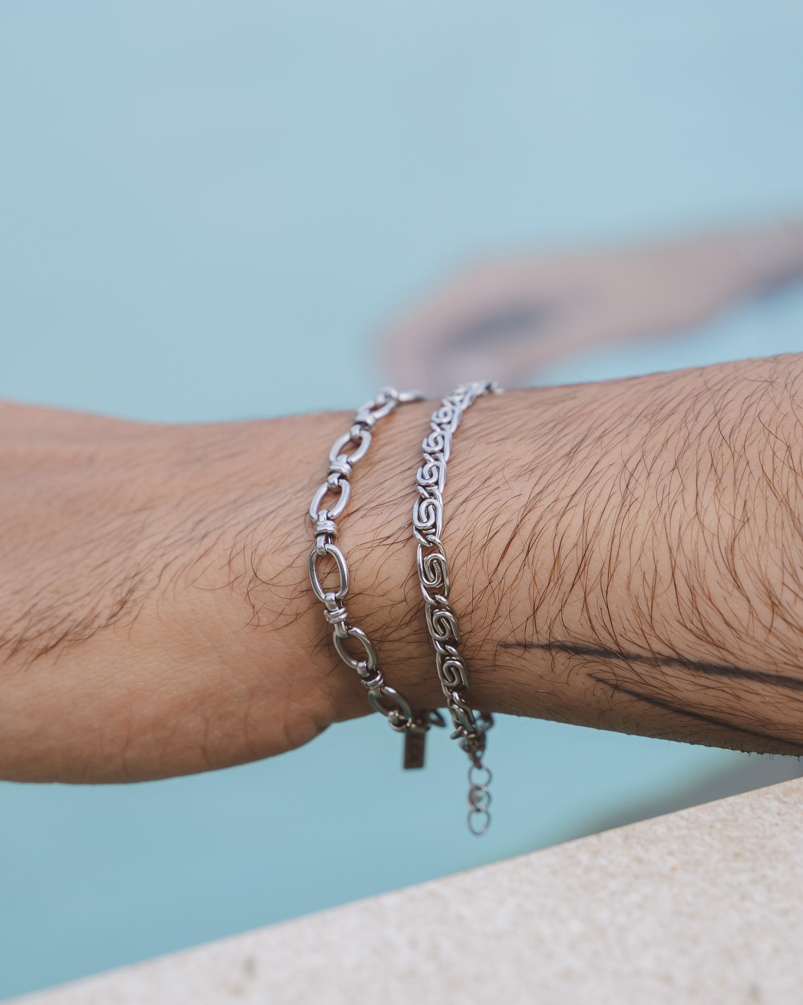 NUSA silver bracelet with chunky linked chain worn on a forearm beside a blue pool