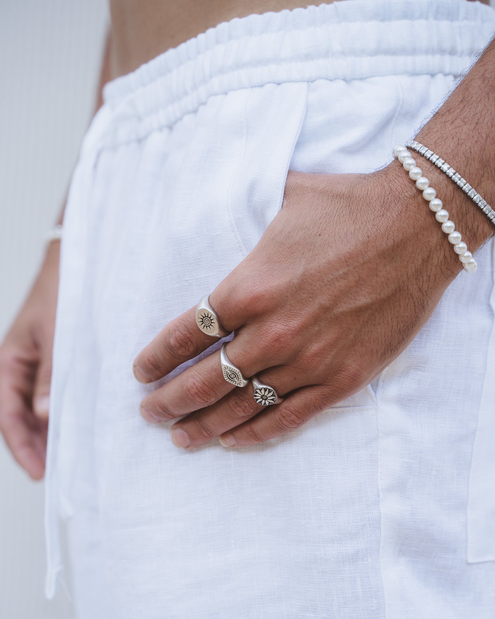 Close up of Fleur Silver Ring with sun motif on a finger with two other rings visible