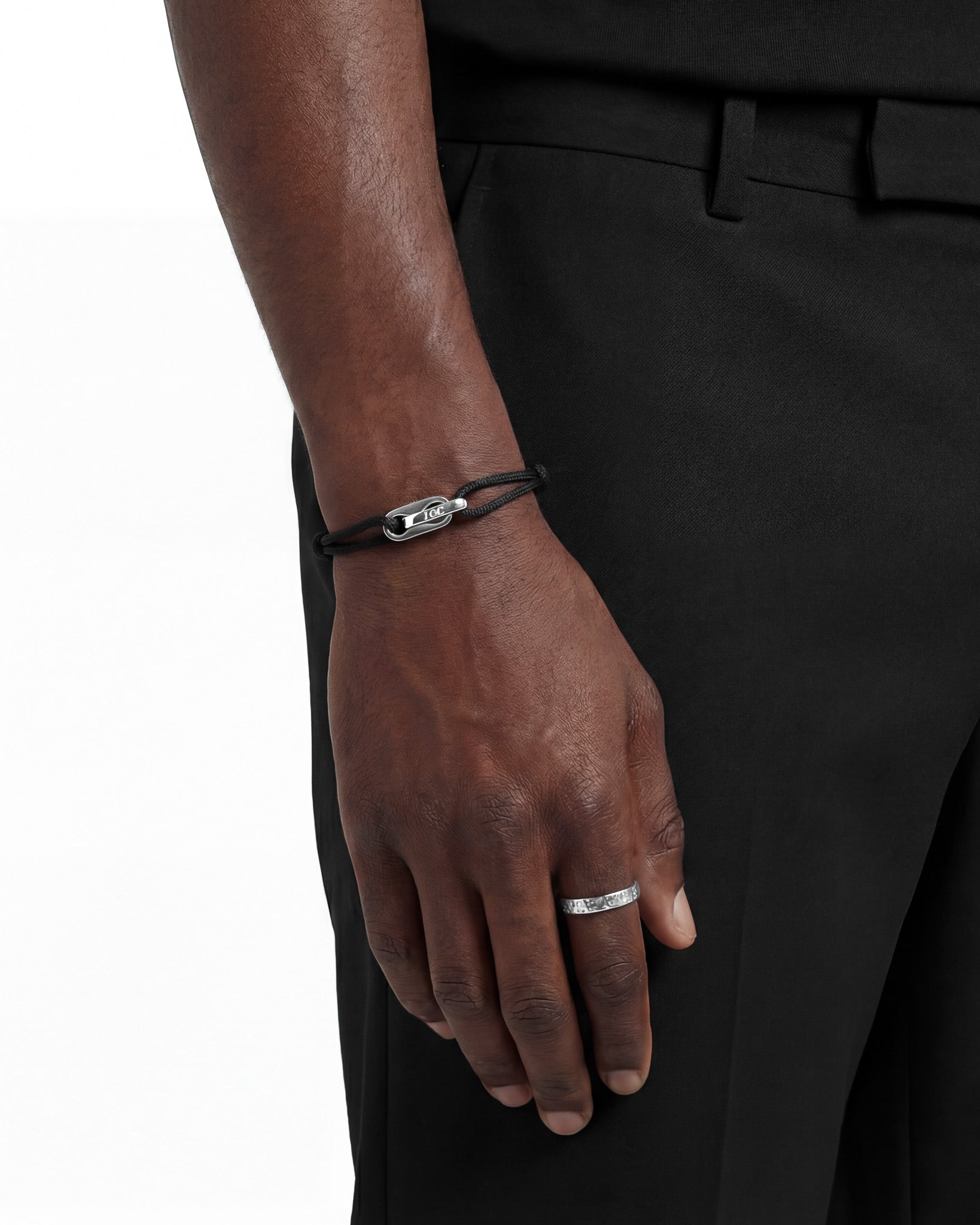 Close up of Atlantis silver bracelet on a dark skinned wrist with a black cord and silver clasp