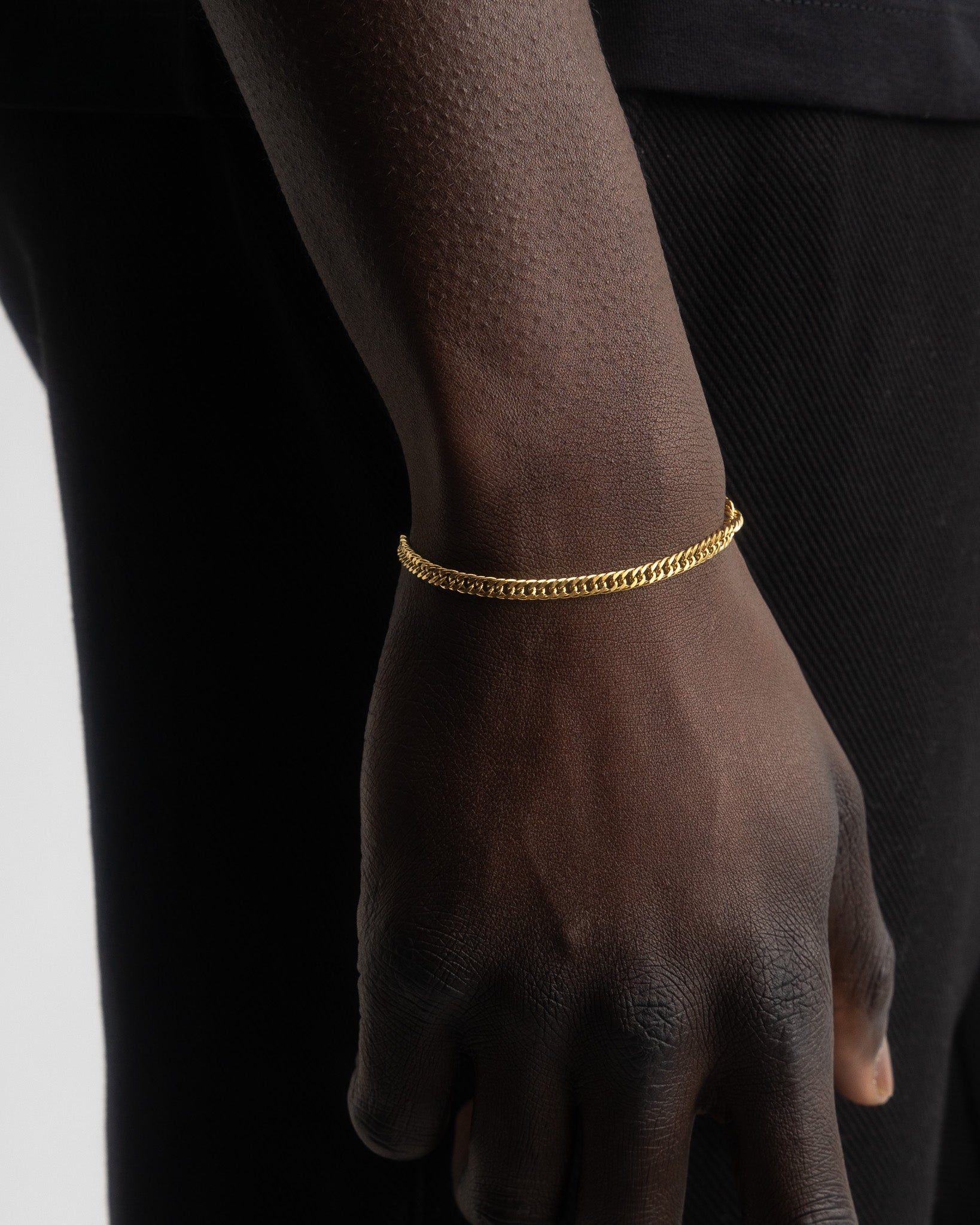 Coral gold bracelet on a model's wrist with adjustable extender chain against black clothing