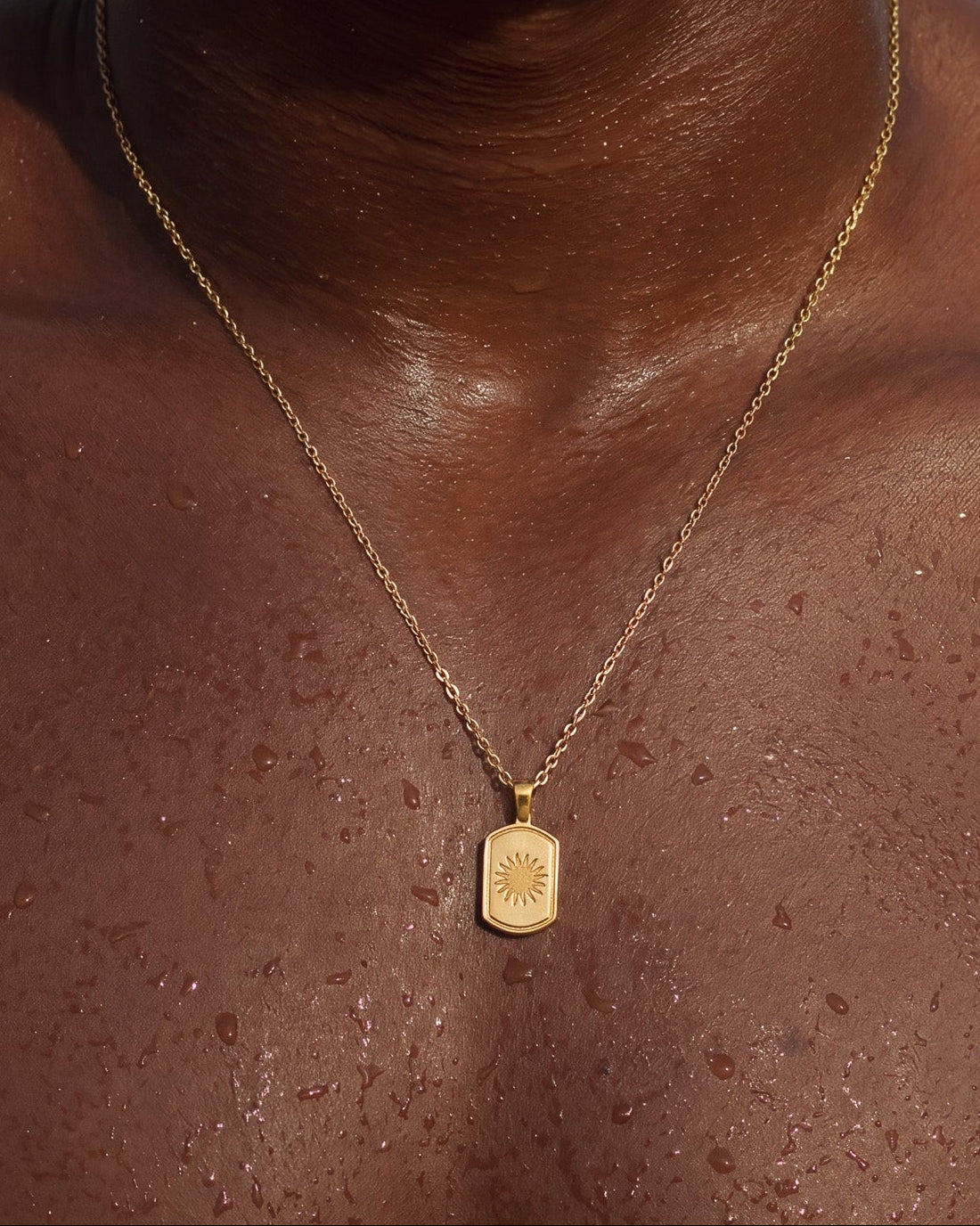Collar dorado DAYSTAR sobre piel oscura con colgante rectangular de sol