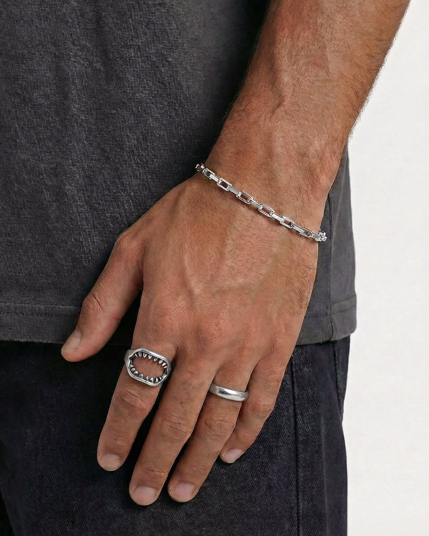 Silver Capri bracelet on a man’s wrist with visible tattoos and dark clothing.