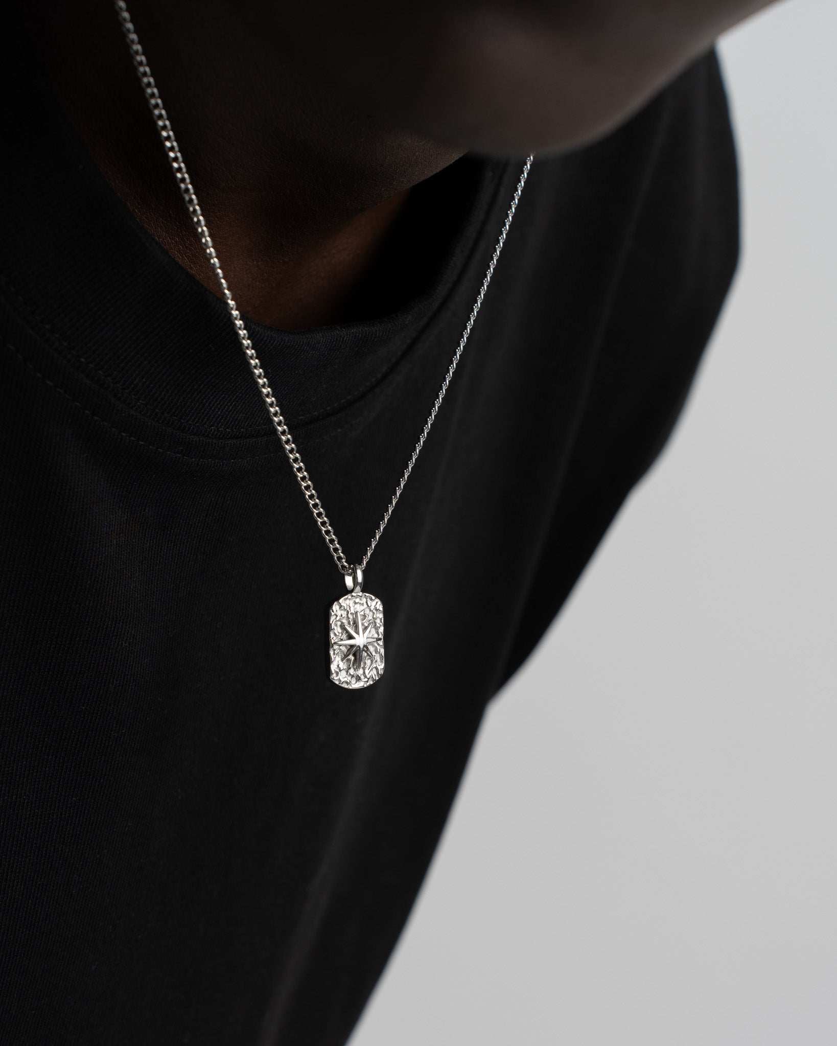 Front view of the IBZ Silver Necklace showing the rectangular crystal pendant resting on a black tee