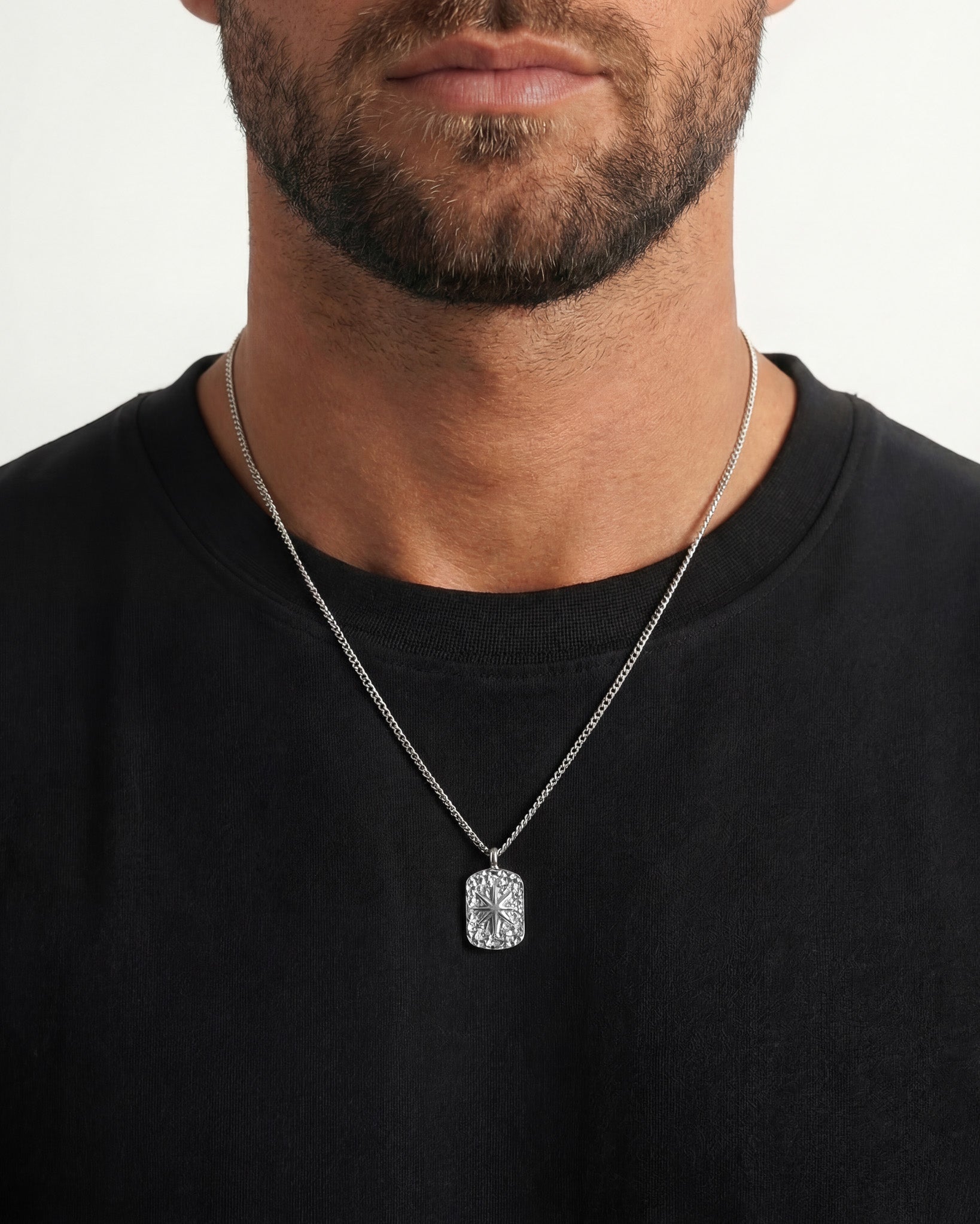 Close up of a man wearing an IBZ Silver Necklace with a crystal rectangular pendant against a black shirt