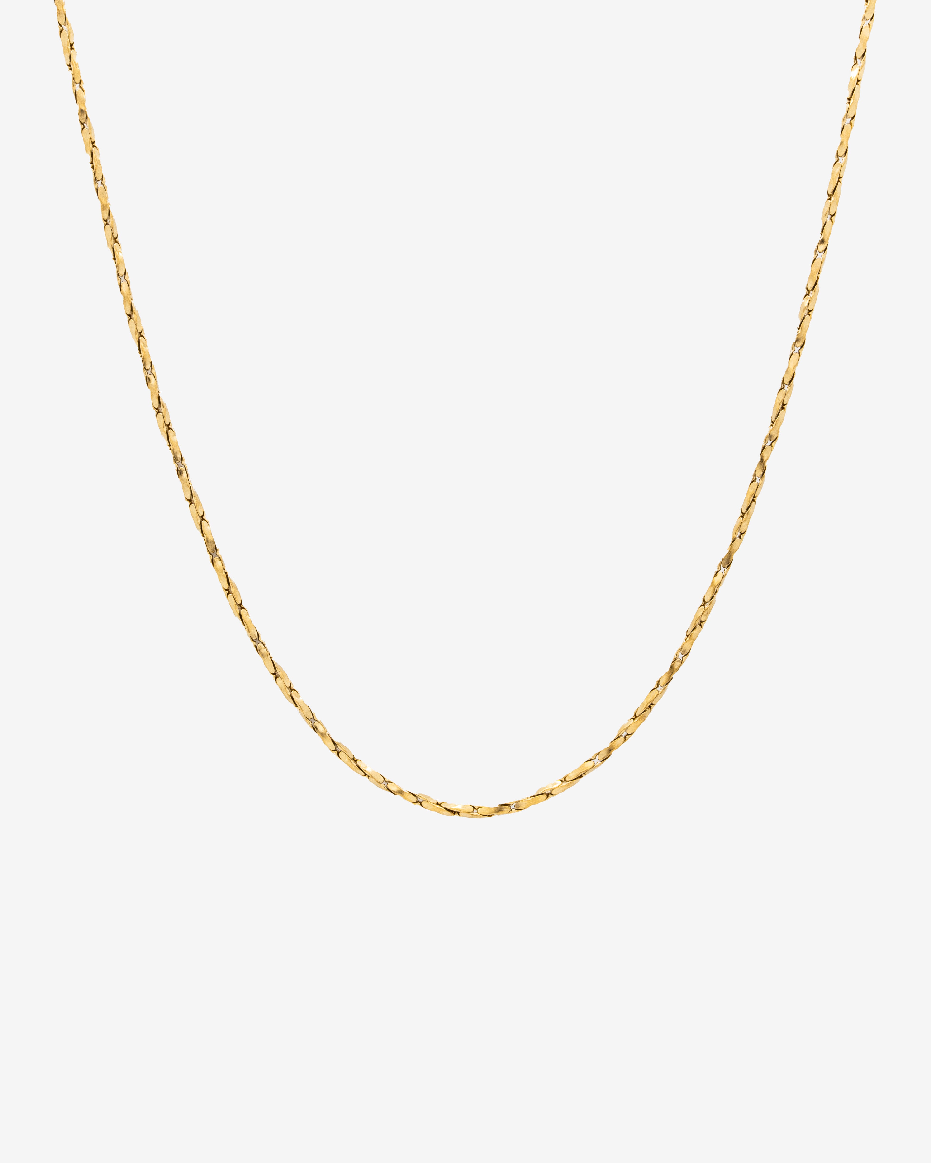 Minimal gold chain with a clean flat-link profile against a light background