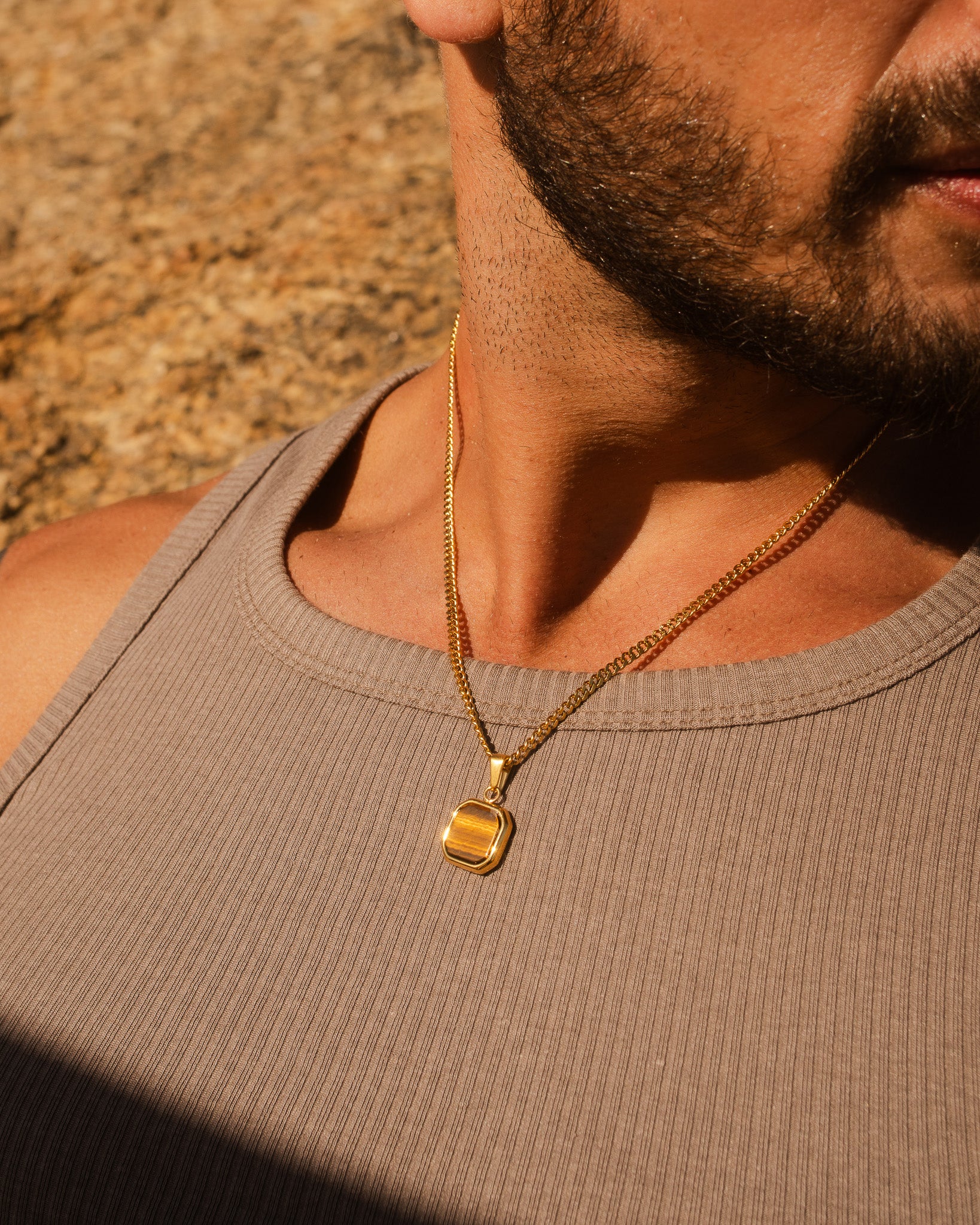 NOVA GOLD NECKLACE en primer plano sobre el pecho de un hombre mostrando cadena dorada y colgante.