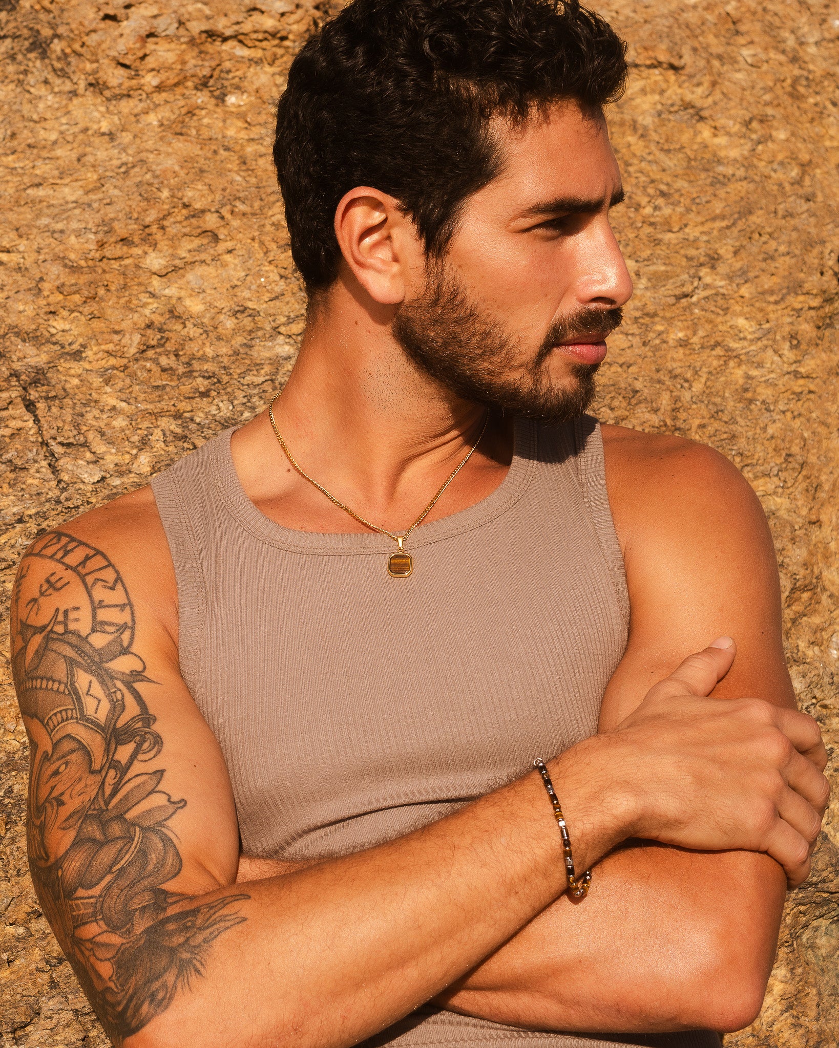 Perfil de un hombre con el NOVA GOLD NECKLACE sobre fondo rocoso.