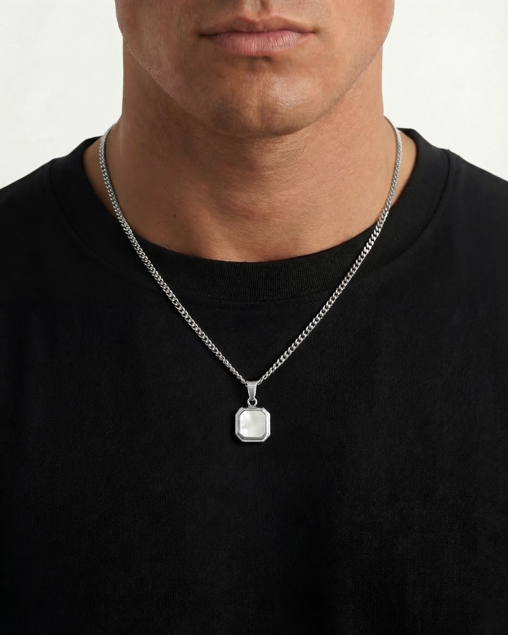 Model wearing NOVA Silver Necklace with a thick curb chain and square framed pendant on a black shirt