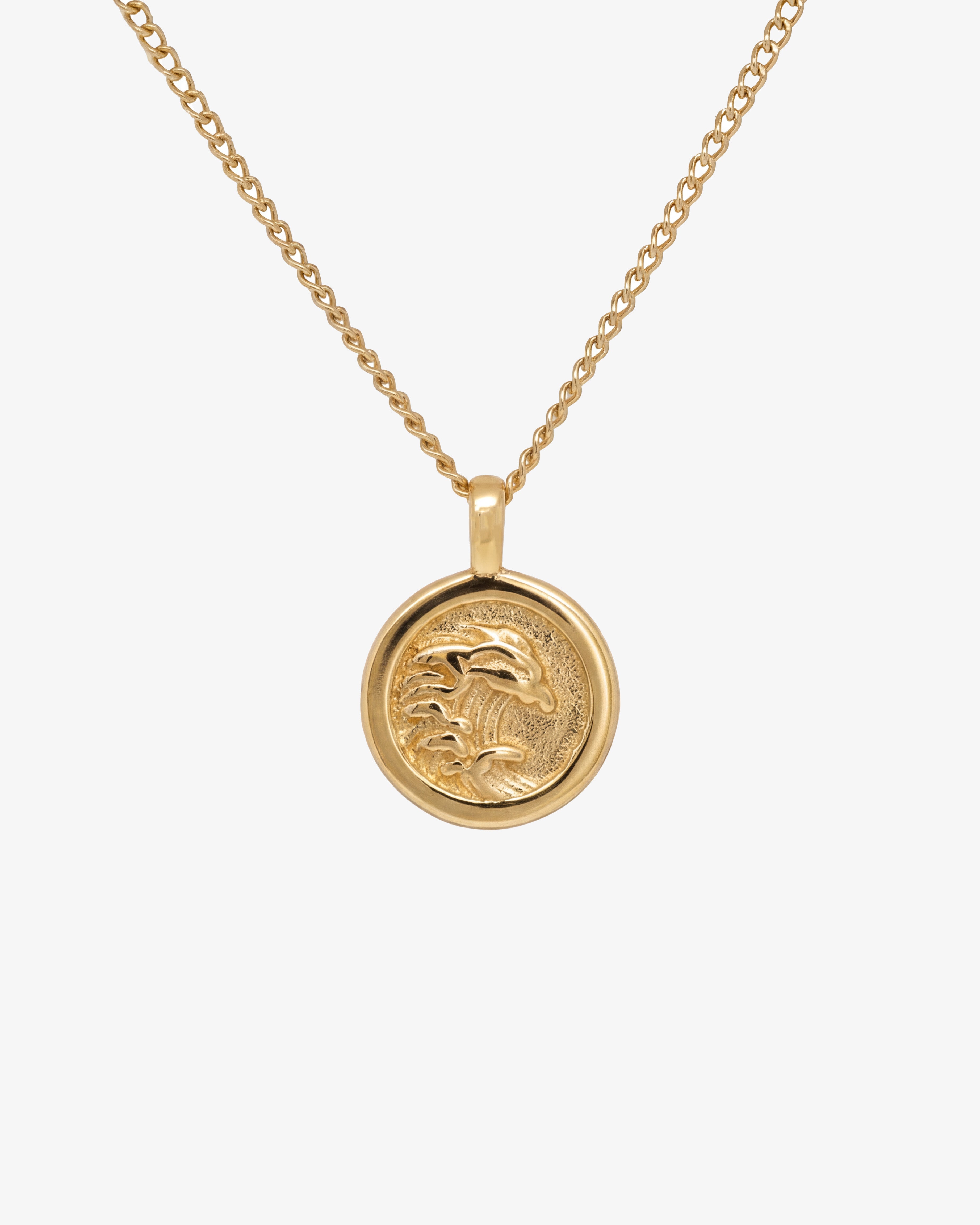 Gold OAHU necklace with a round palm tree pendant on a pale background