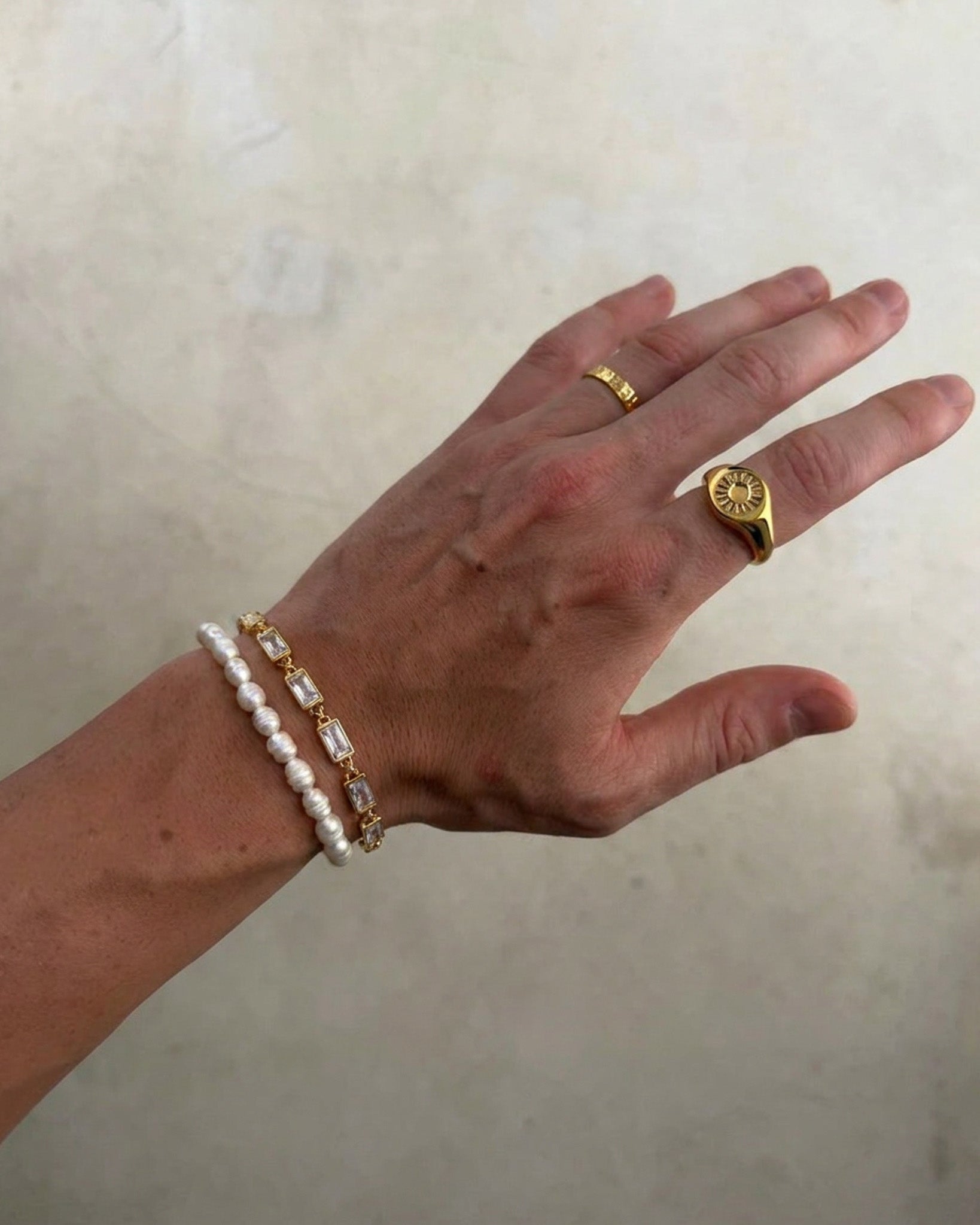 Pulsera dorada OMEN con eslabones cuadrados texturizados en la muñeca.
