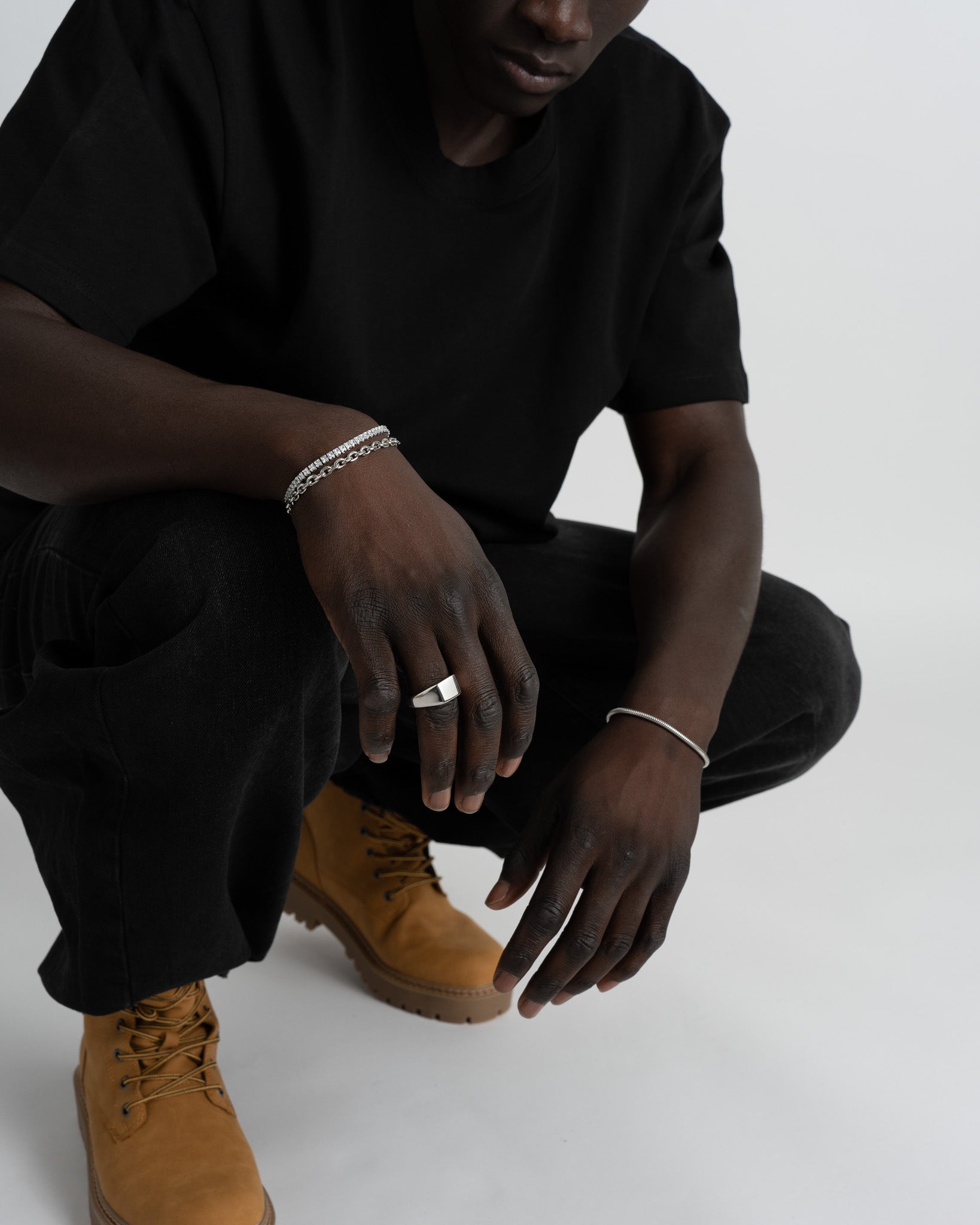 Wrist adorned with several silver bracelets including the Sunset Silver Bracelet against a black shirt.