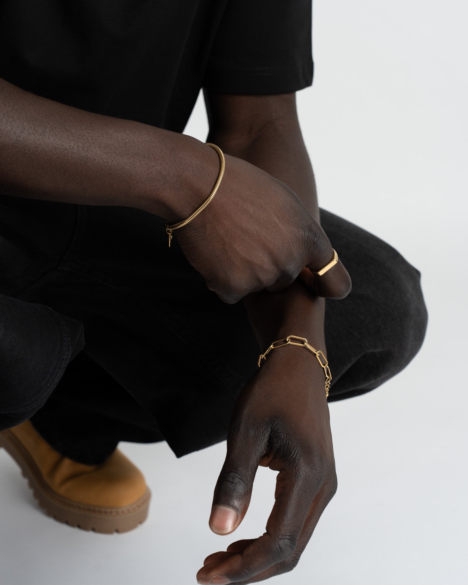 Sunset Gold Bracelet with delicate link design on the wrist against a black sleeve.