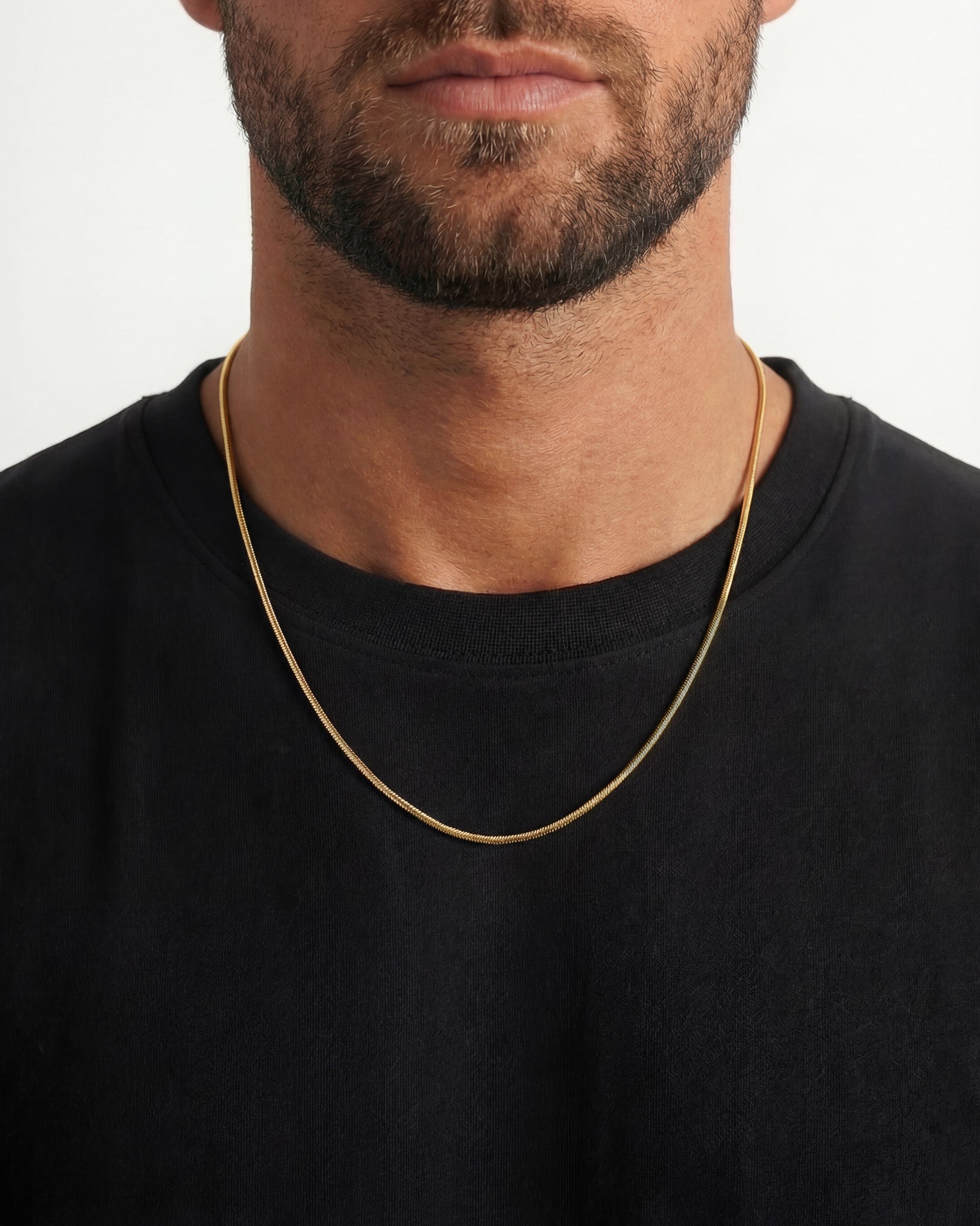 Close up of a man wearing the Sunset Gold Chain necklace with a beard and black shirt