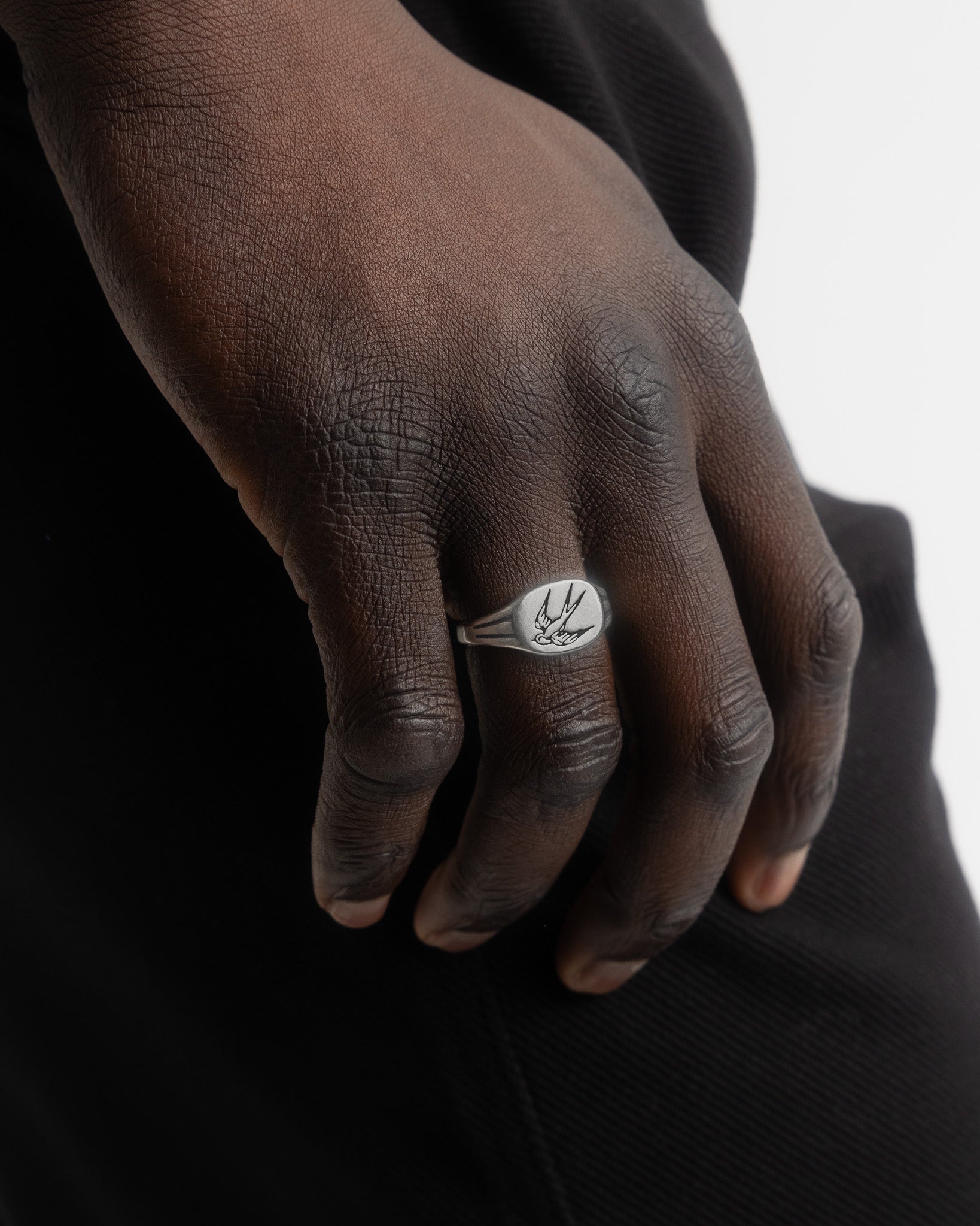 Close view of swallow ring on finger showing the bird engraving on the round face