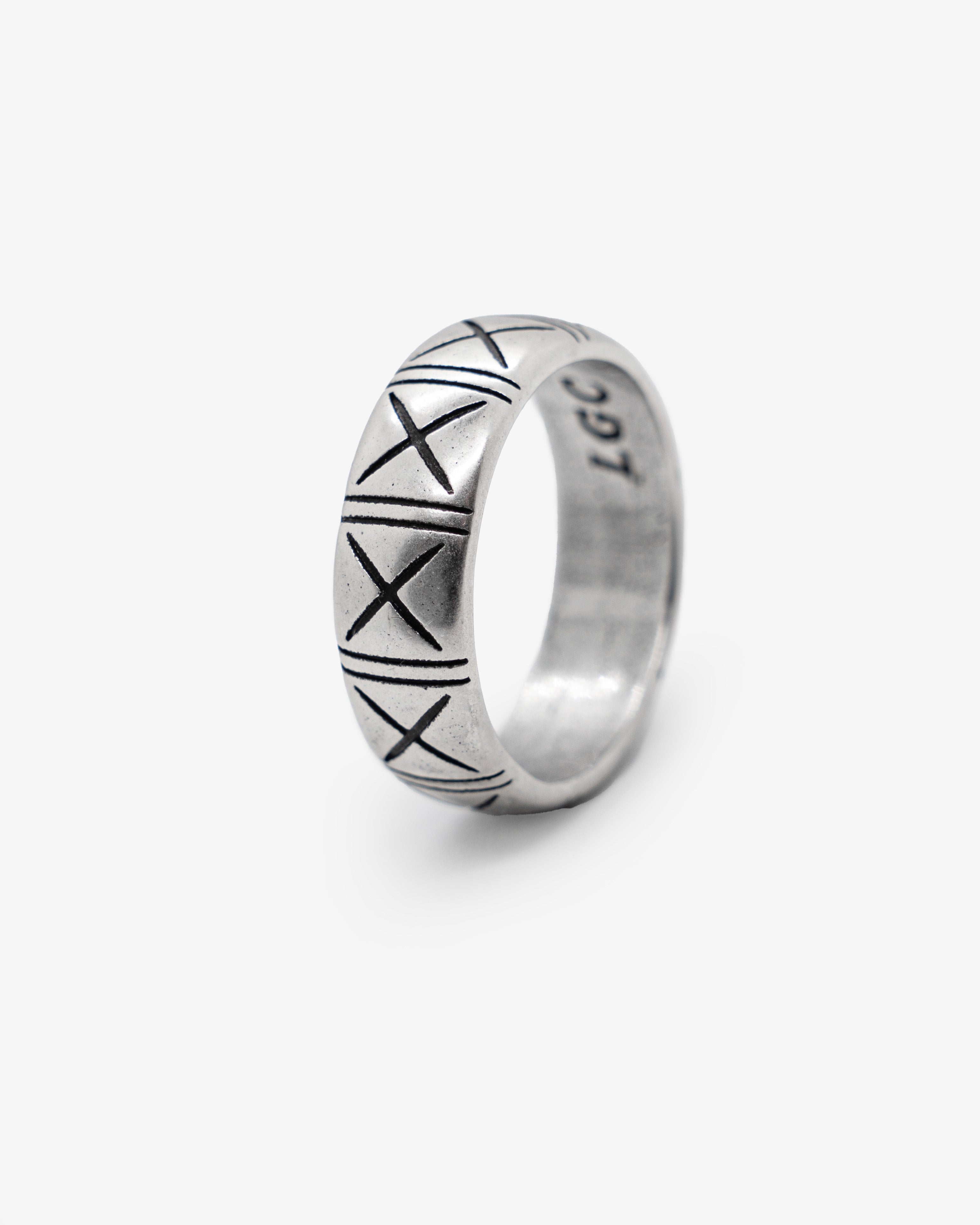 Close-up of a silver TNF ring with X engravings around a rounded band