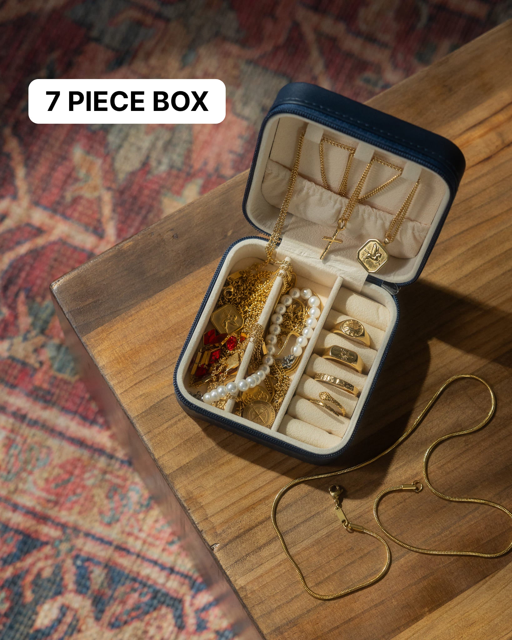 Open jewelry box on a wooden surface filled with gold chains pendants and a pearl necklace
