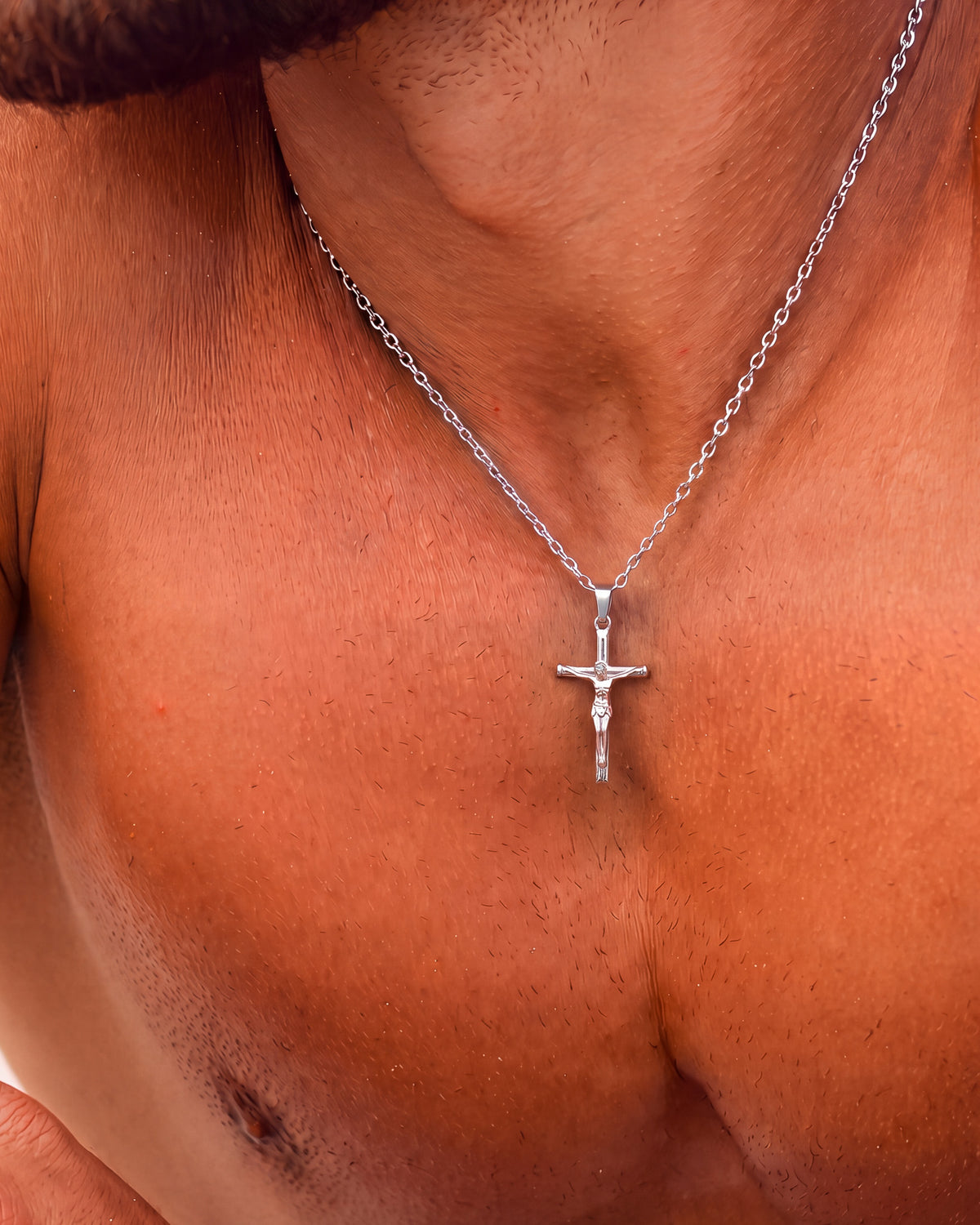 Collar de plata con crucifijo en el cuello, con el colgante a la altura de la clavícula