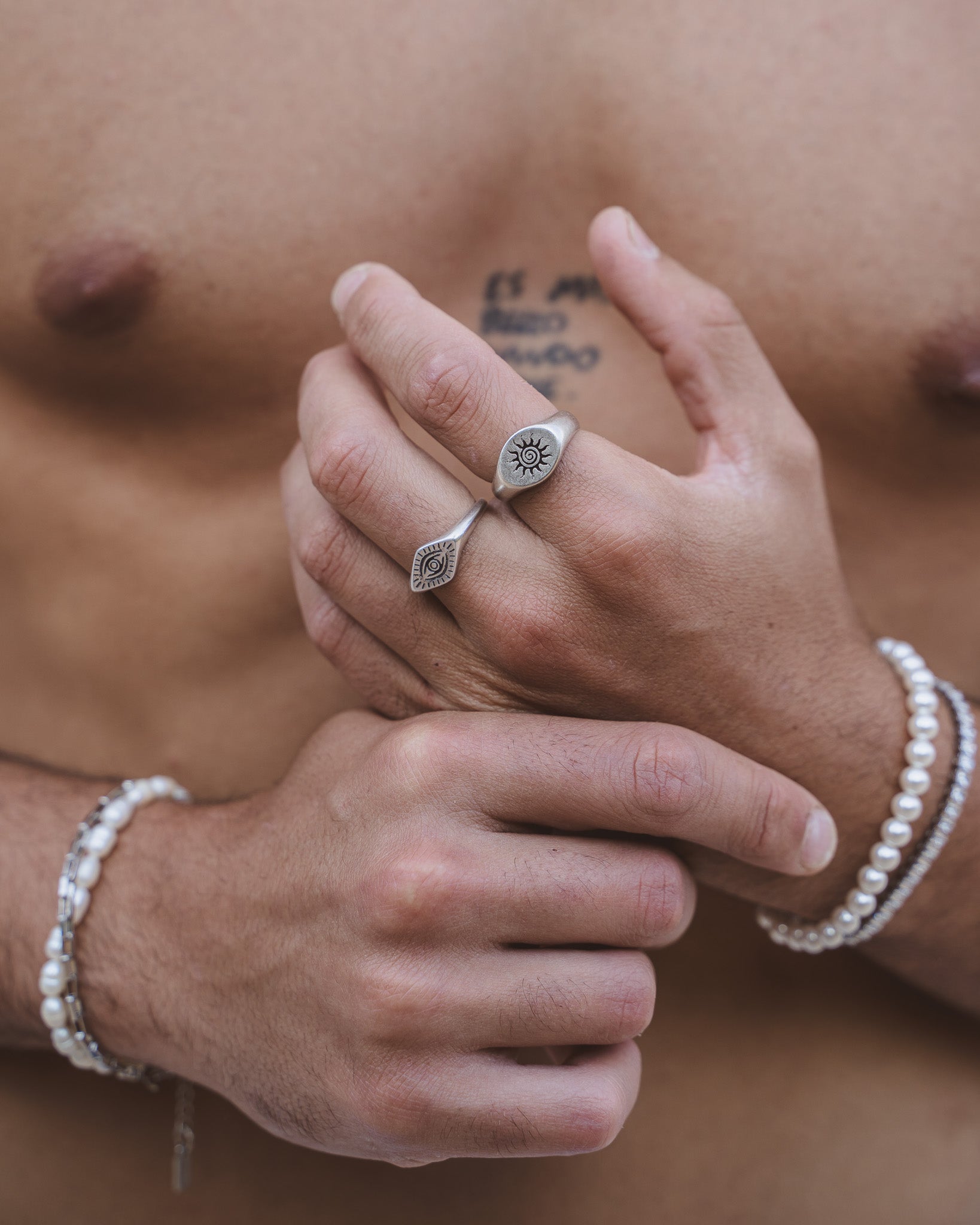 Two silver rings on fingers with the ENERGY SILVER RING showing a sun spiral design on one finger