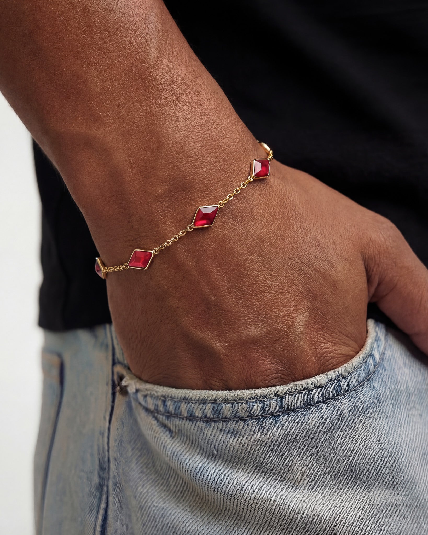 Amberes gold bracelet with red square gemstones along a fine chain worn on the wrist