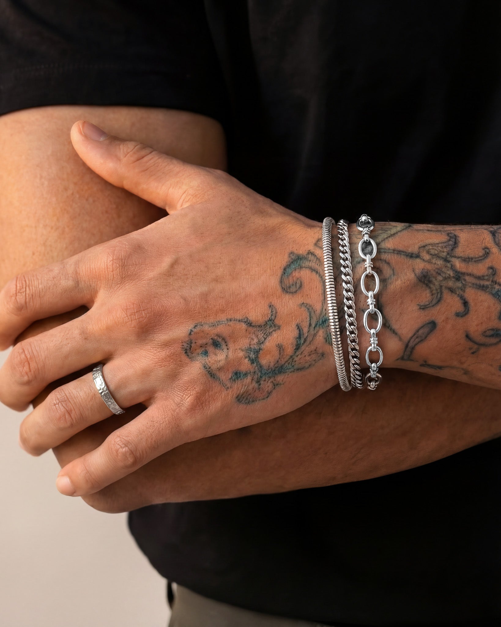 Close up of a tattooed wrist wearing multiple BYBLOS silver bracelets
