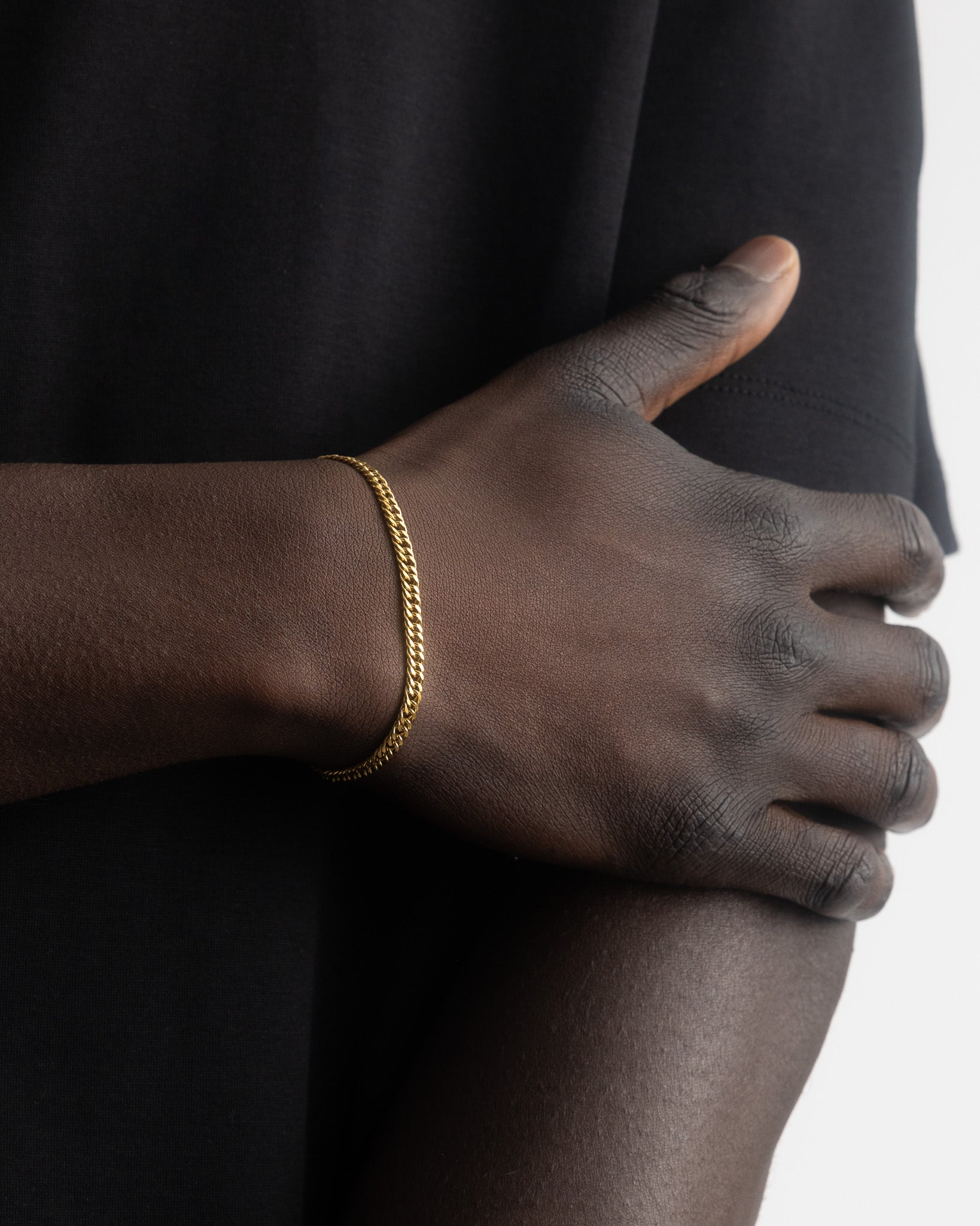 Coral Gold Bracelet on a dark-skinned wrist against a black top; rope chain style