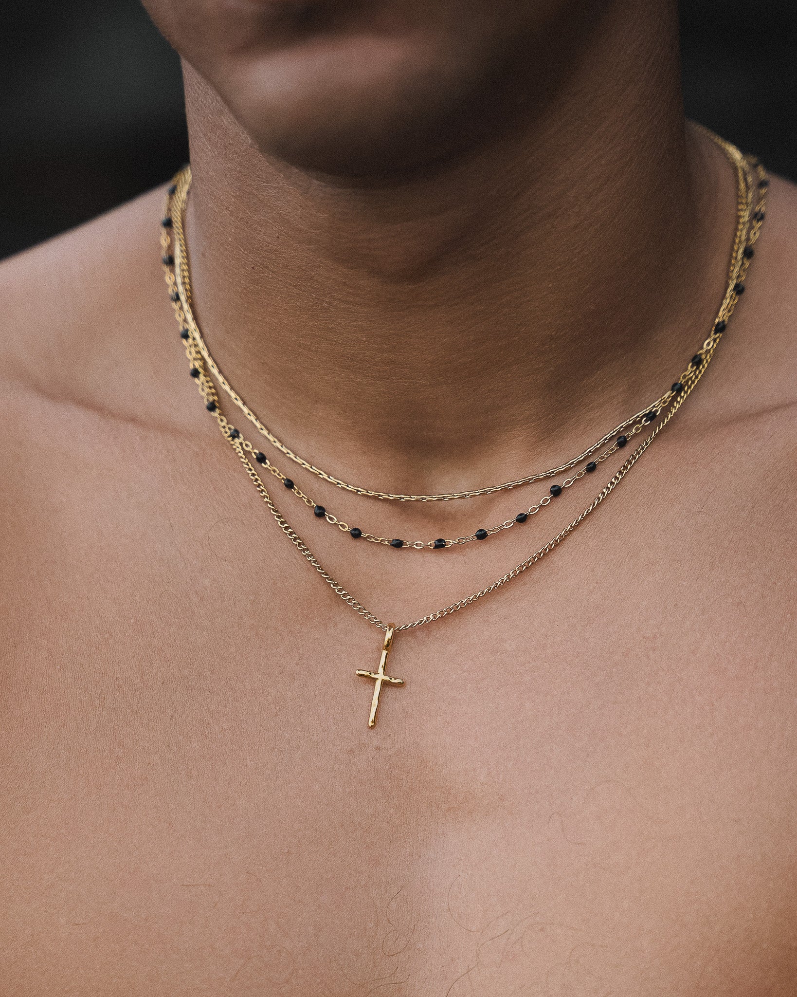 Gold chain necklace with black beads draped around a model's neck