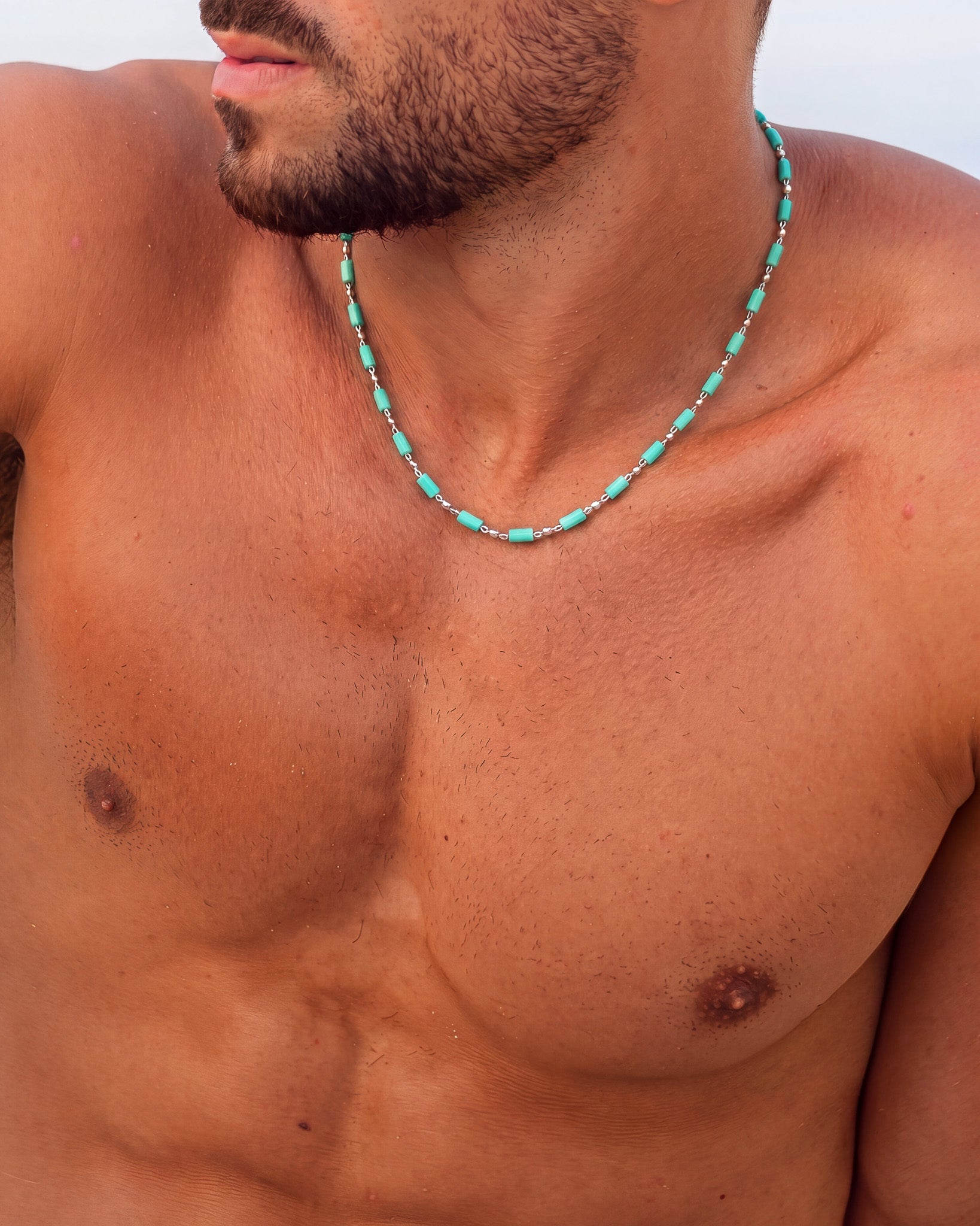 Hombre con collar de cuentas cúbicas turquesa y cadena de plata en el cuello