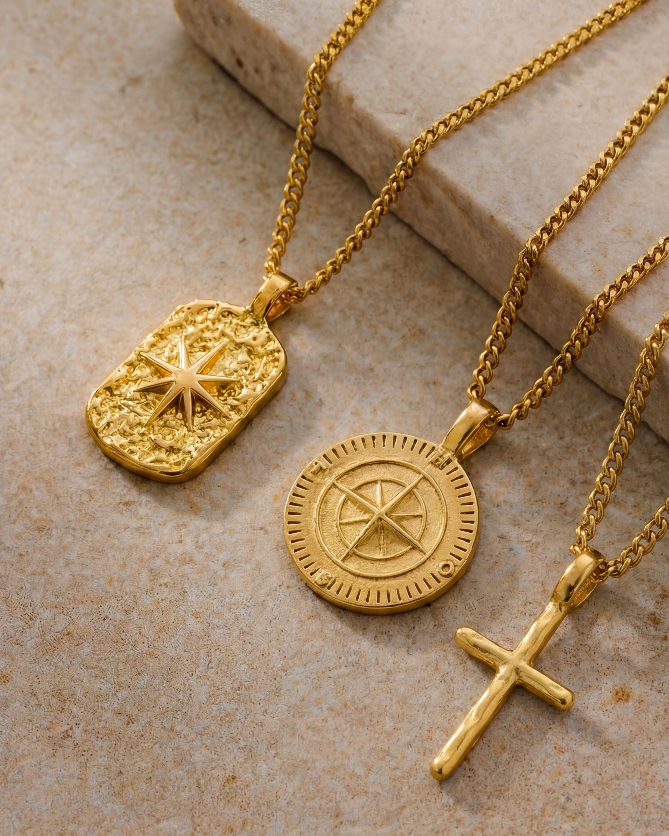 three gold necklaces in a stone surface