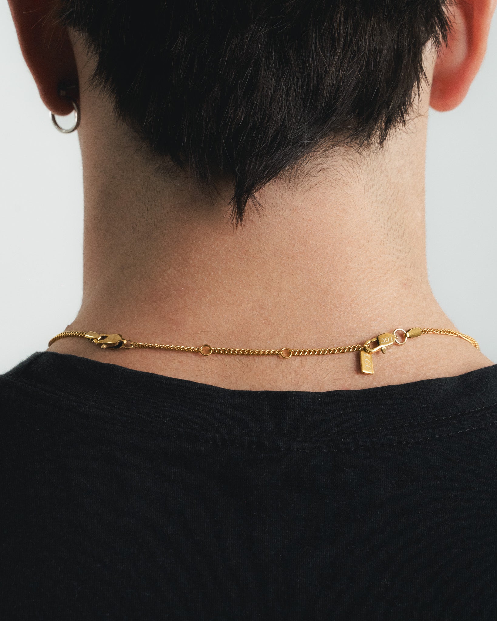 Back view of a neck wearing a gold chain extender connected to a necklace