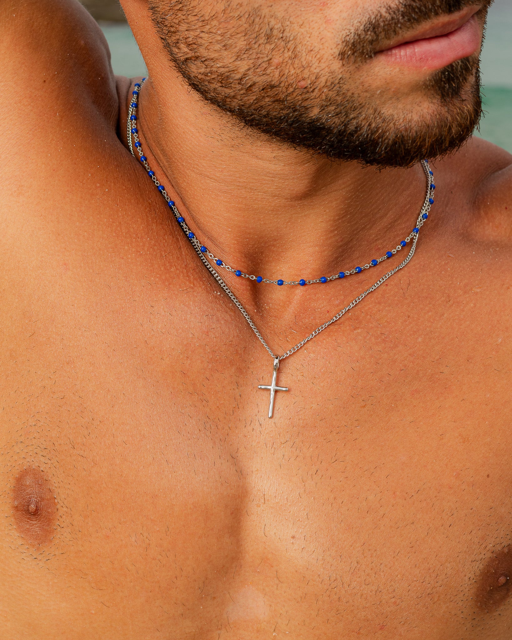 Primer plano de un collar de cadena de plata con cuentas turquesa en el cuello.