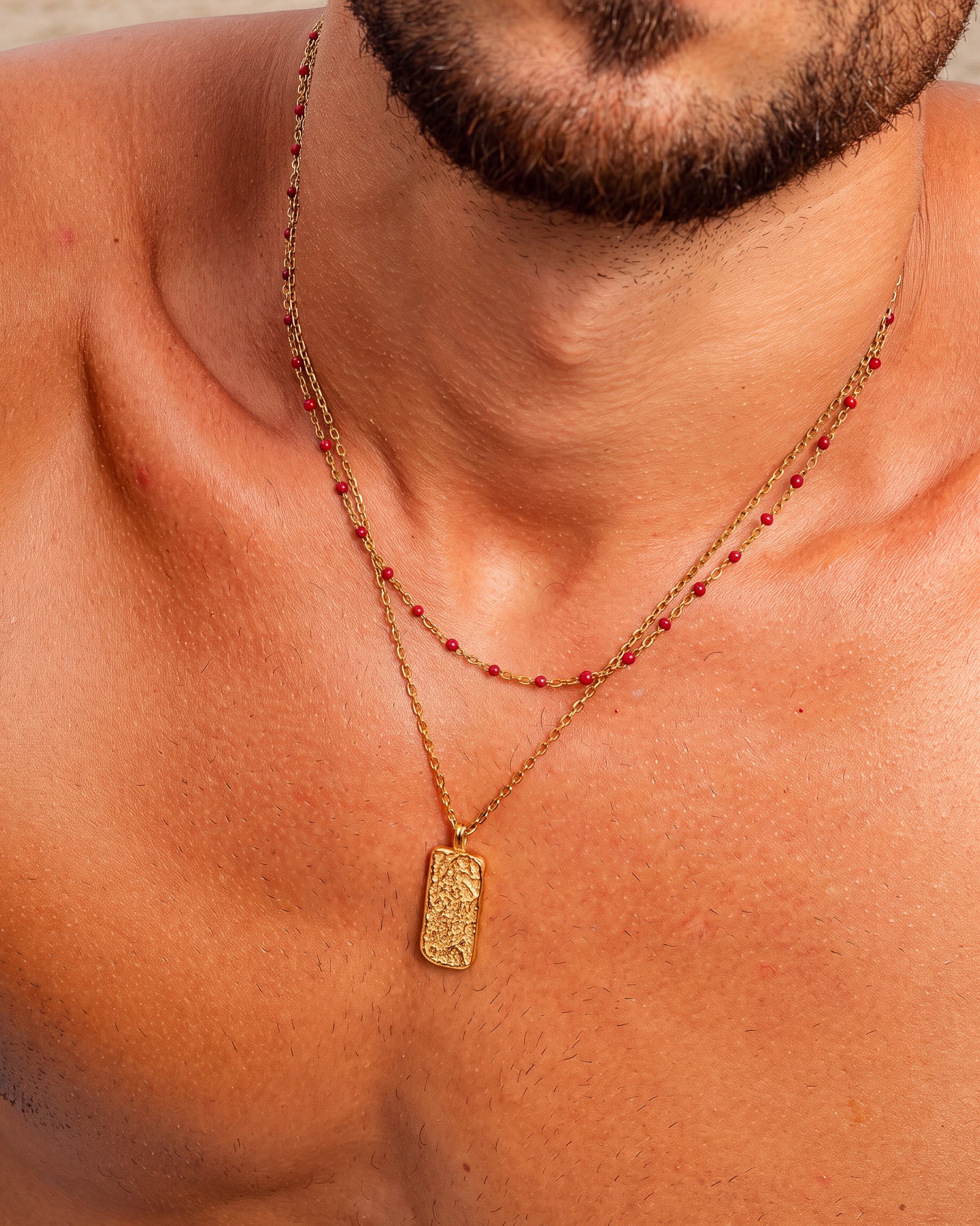 Hombre con una cadena de oro con detalles de cuentas rojas en el cuello