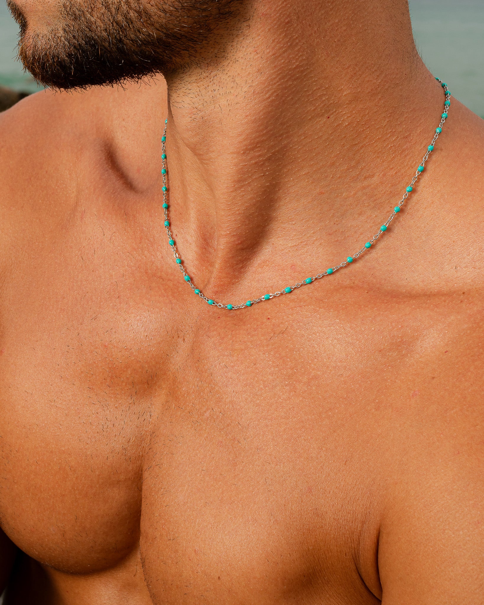 Collar de cadena de plata con cuentas turquesa en el cuello de un hombre