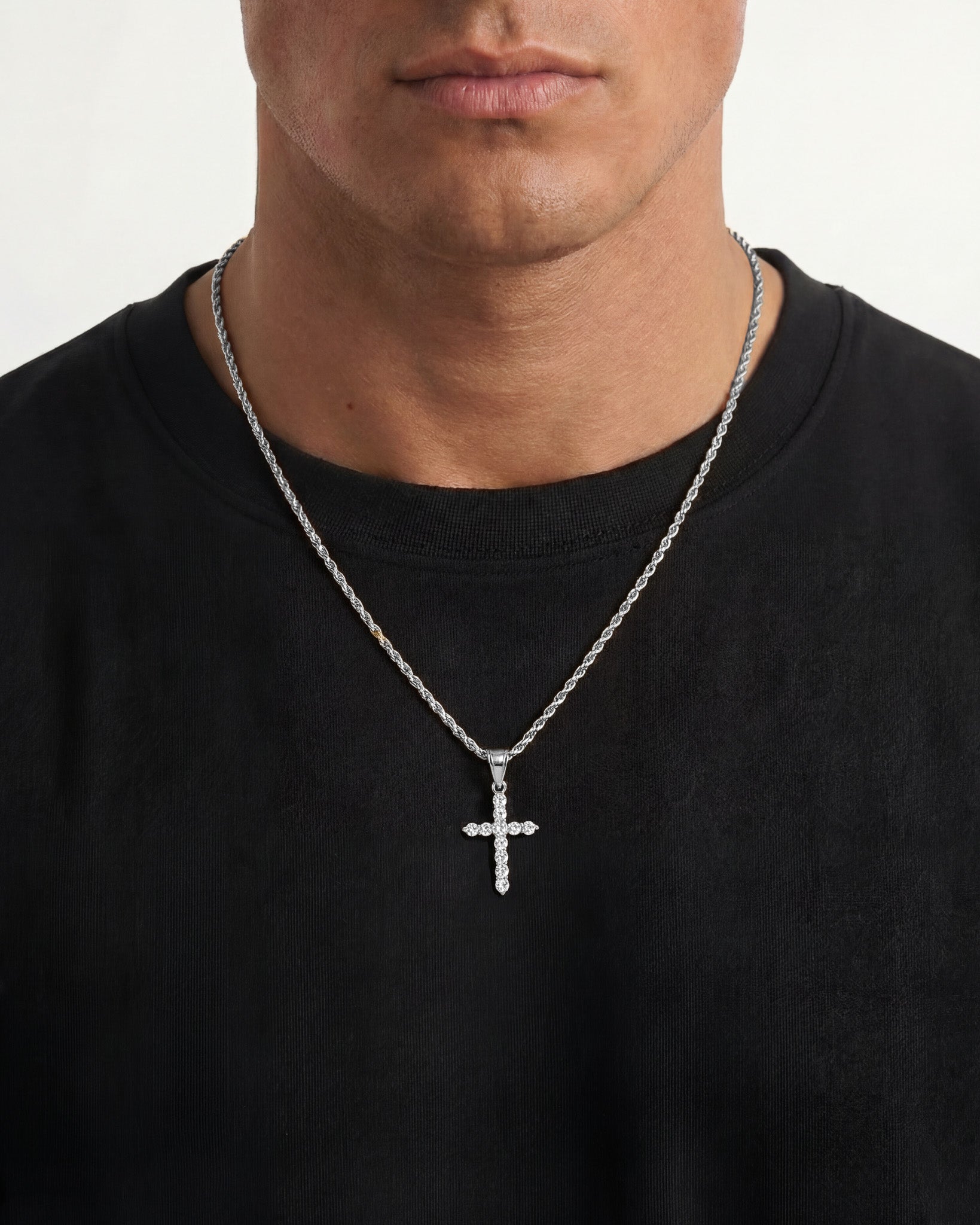 Man wearing ICY CROSS silver necklace with a zircon crystal cross pendant against a black shirt.