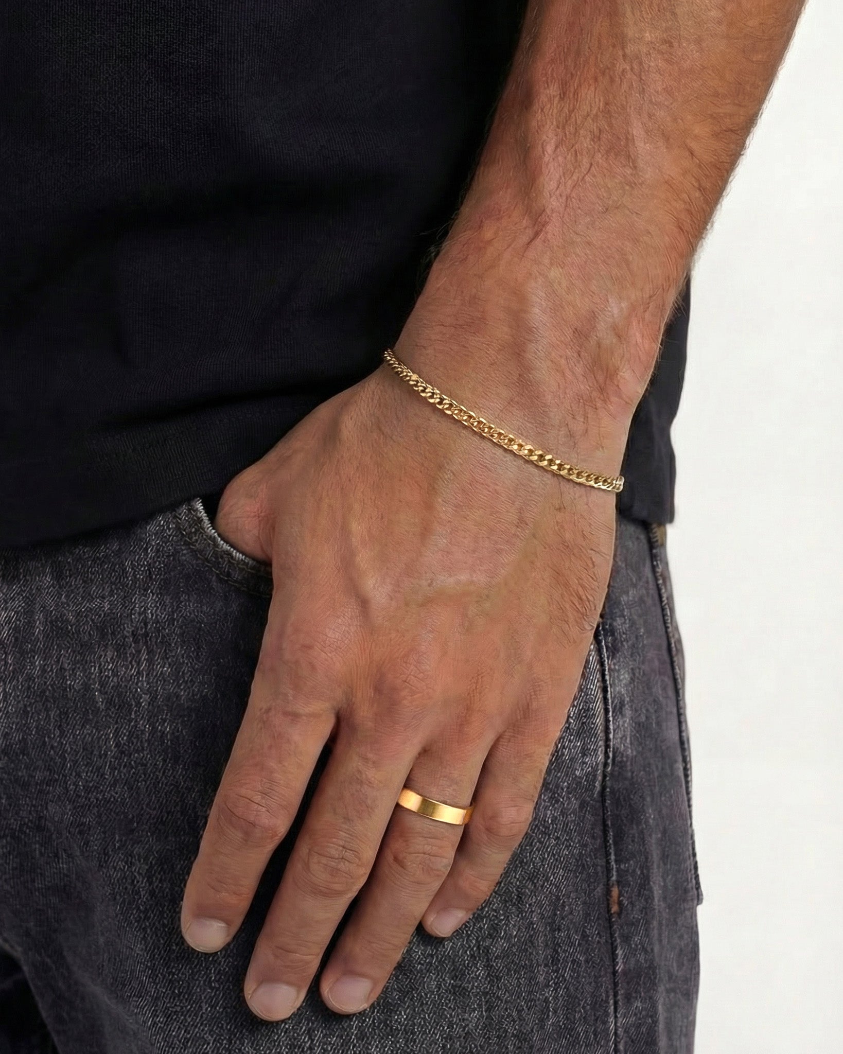 Model wearing a gold chain bracelet and a ring on the same hand