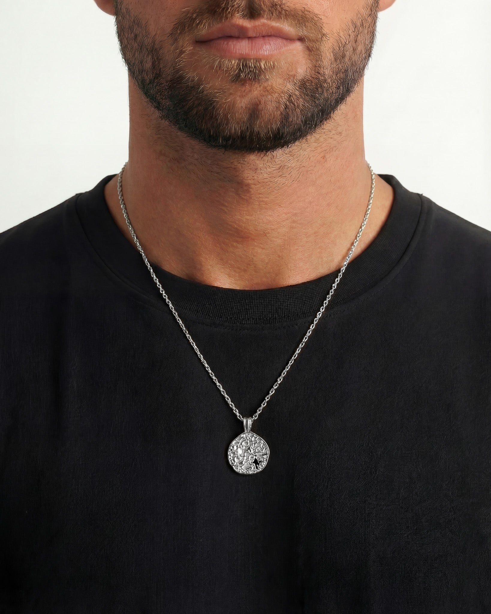 Man wearing a MIST SILVER NECKLACE with a textured round pendant on a silver chain