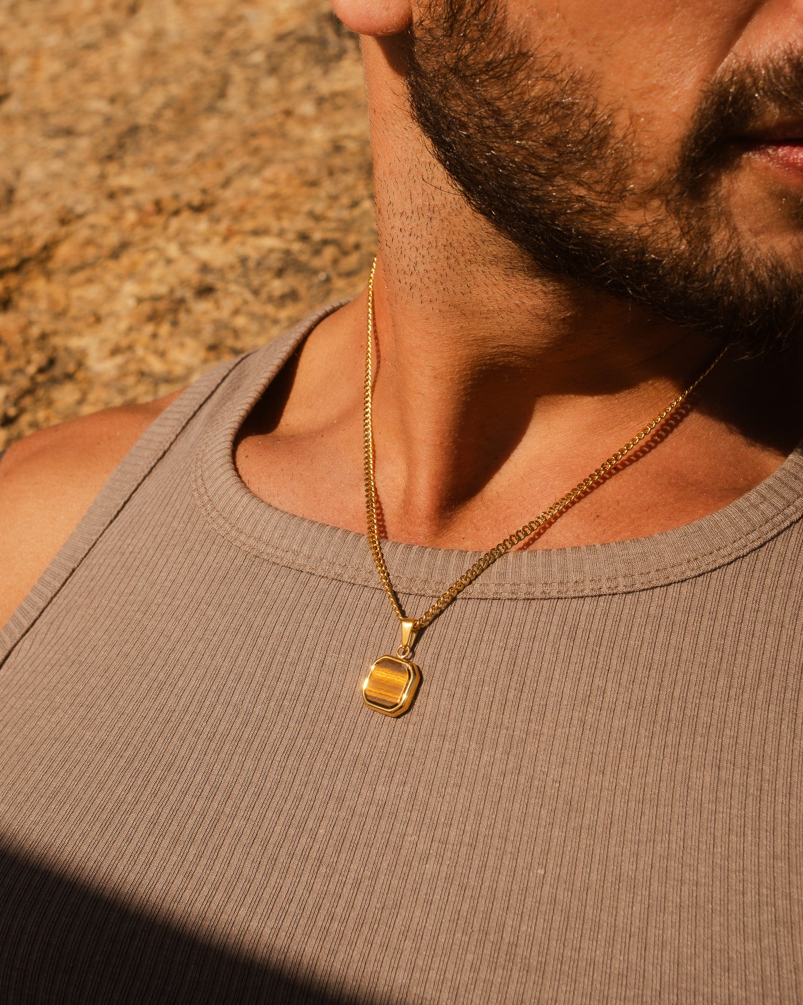 NOVA GOLD NECKLACE close up on a man's chest showing a gold chain and pendant.