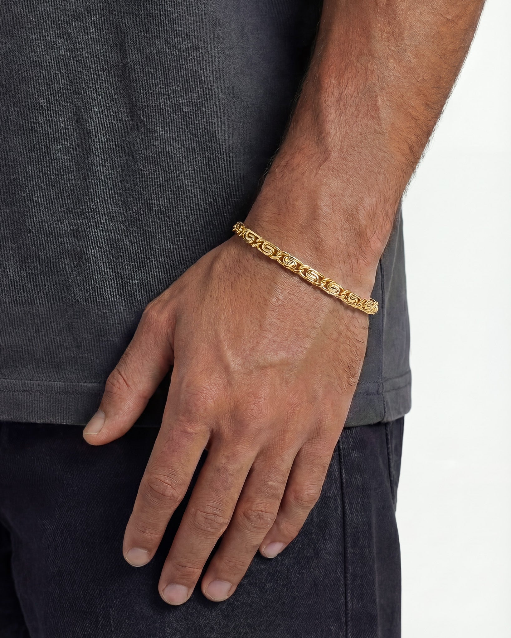 NUSA gold bracelet on a man's wrist with close-up of the chain links