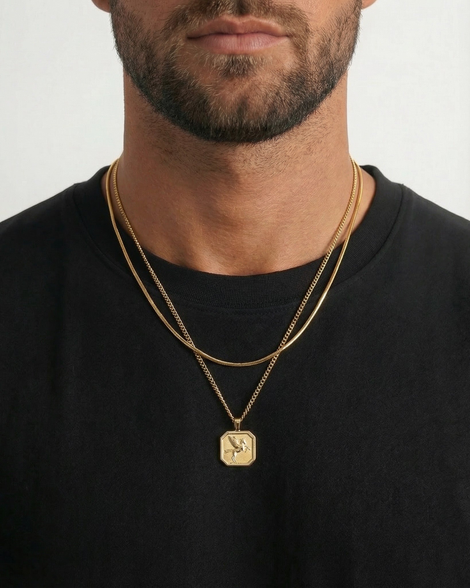 Close up of a man wearing layered gold necklaces around the neck