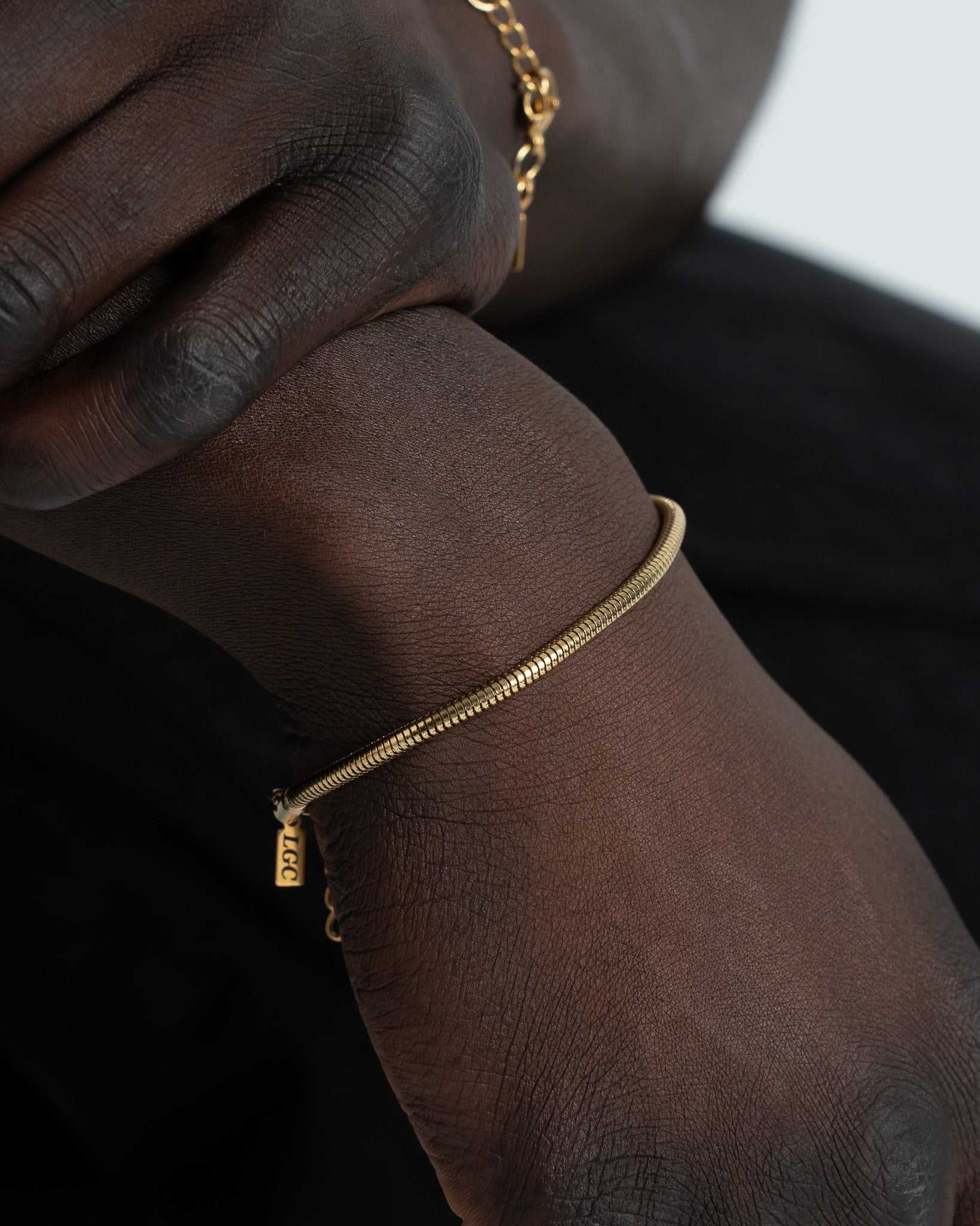Sunset Gold Bracelet with ribbed segmented links around the wrist and a small tag.