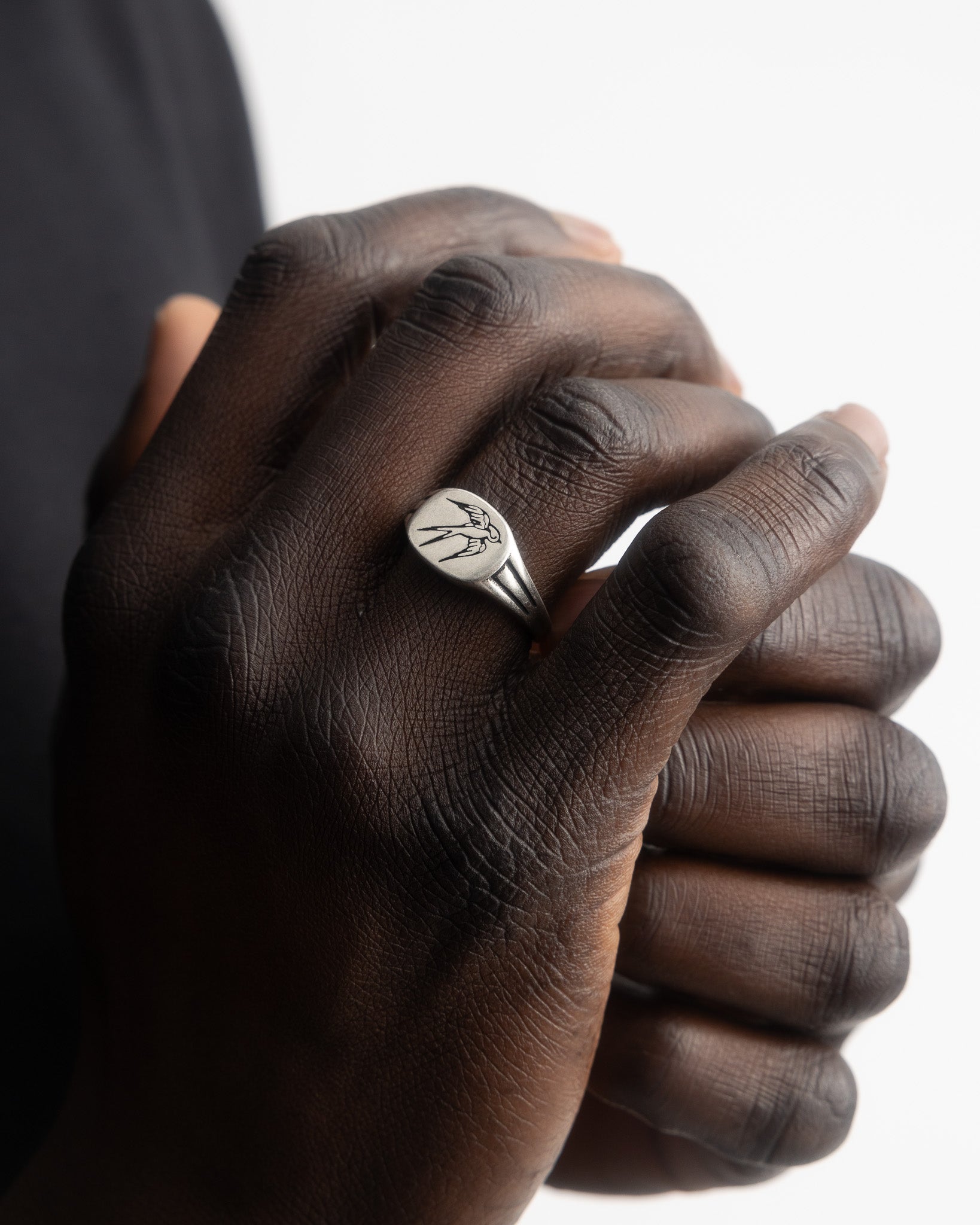 Close up of hand wearing swallow silver ring with round face and bird engraving