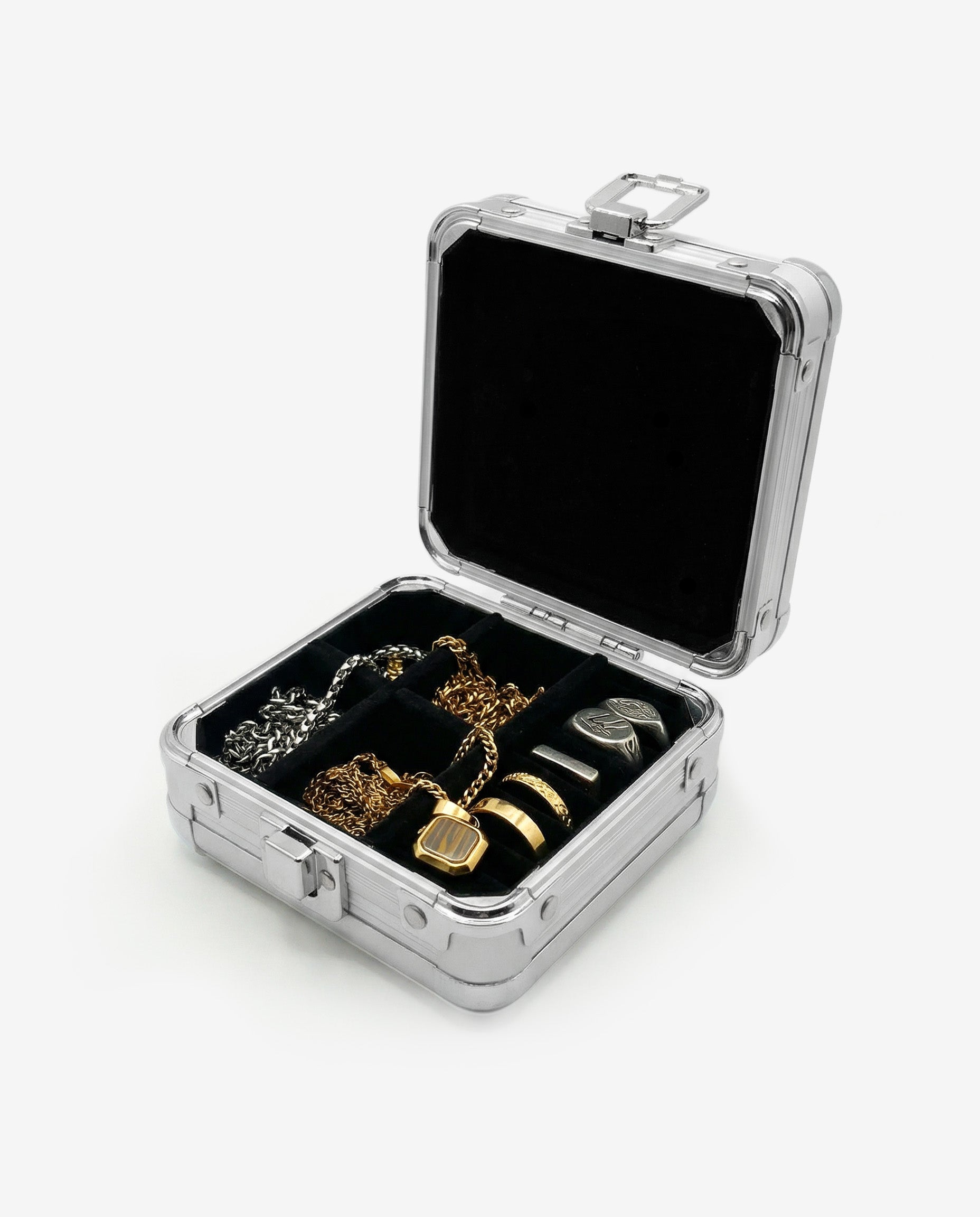 Open metal jewelry box showing black lined interior with gold and silver chains and rings